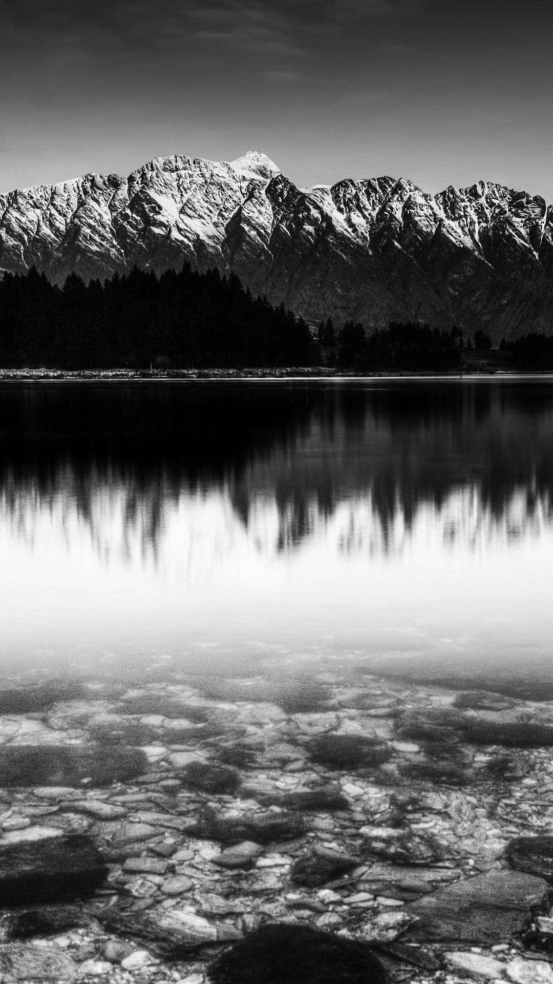A Black And White Photo Of A Mountain Reflected In Water