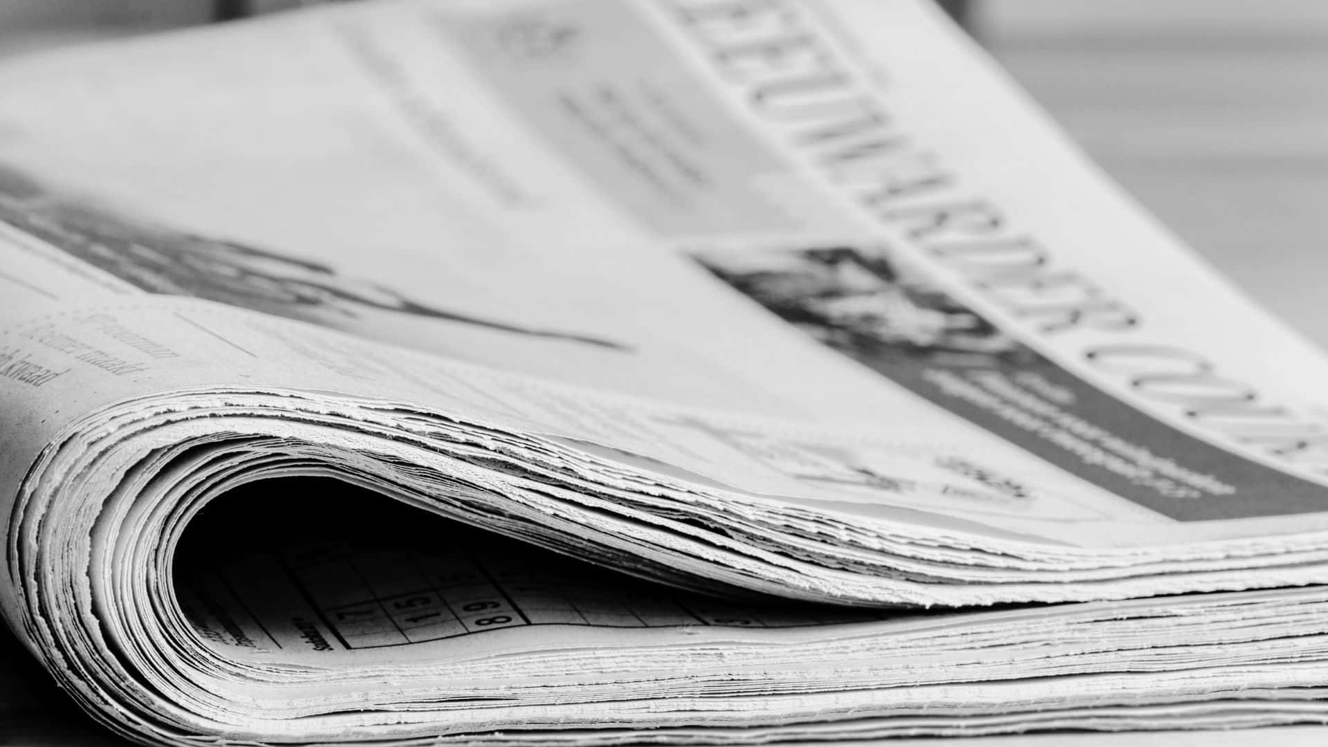 Vintage black and white newspaper on a wooden table Wallpaper