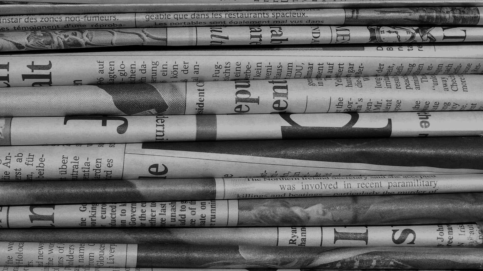 Vintage black and white newspaper on a wooden table Wallpaper