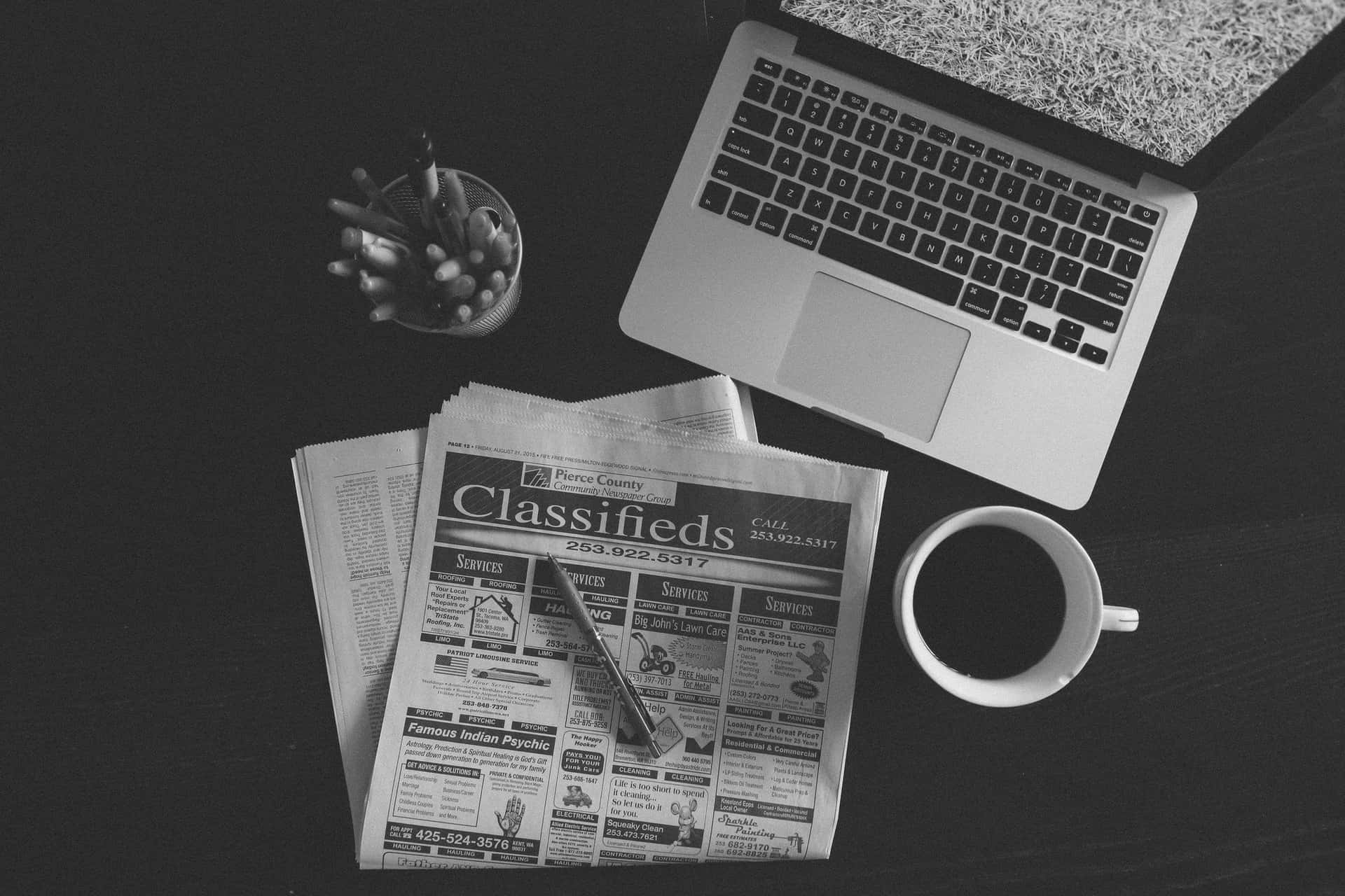 Vintage black and white newspaper on a table Wallpaper