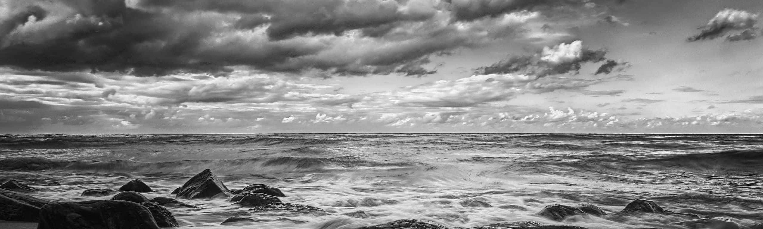 A serene black and white ocean scene featuring calm waves Wallpaper