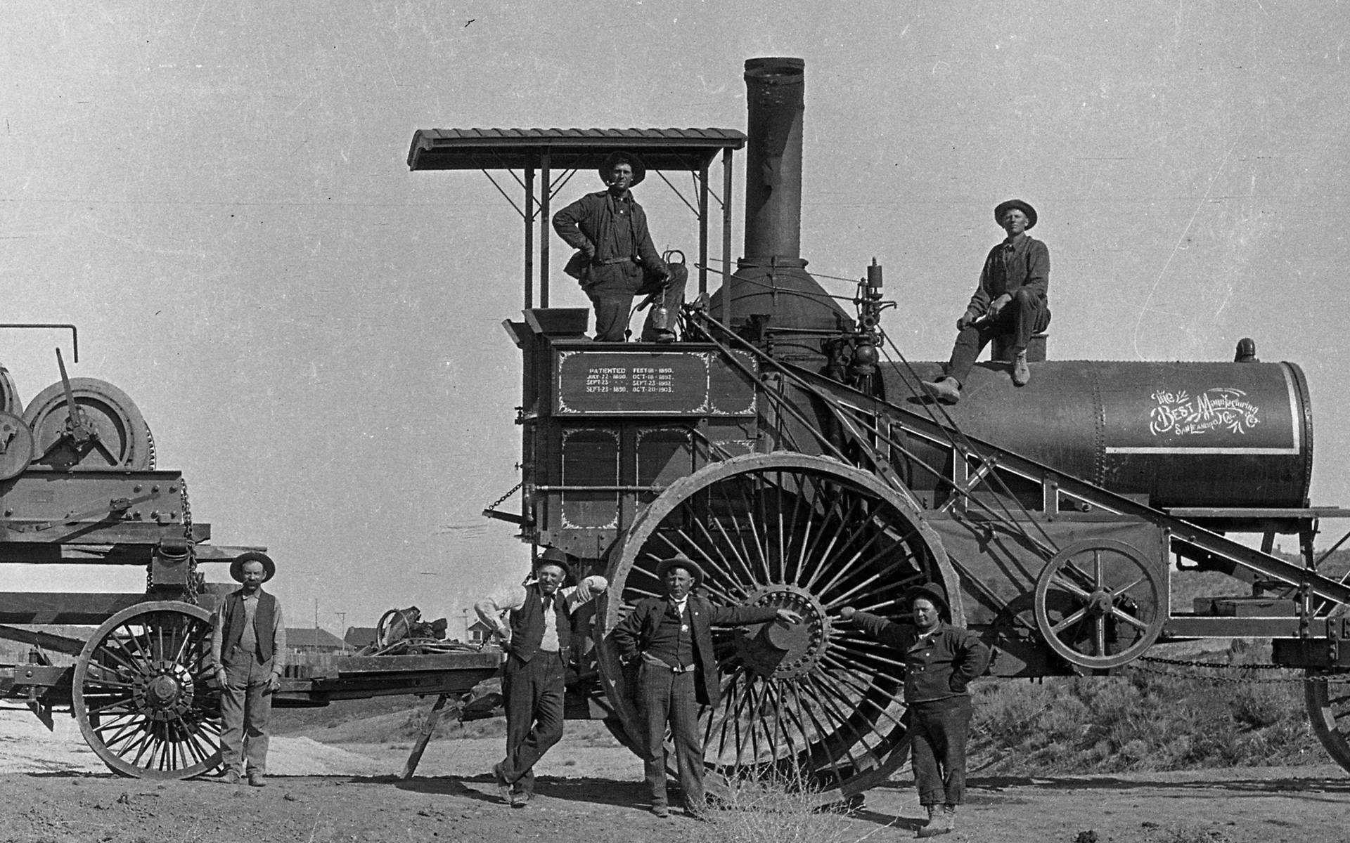 Vintage Black and White Photo of People with Steam Tractor Wallpaper