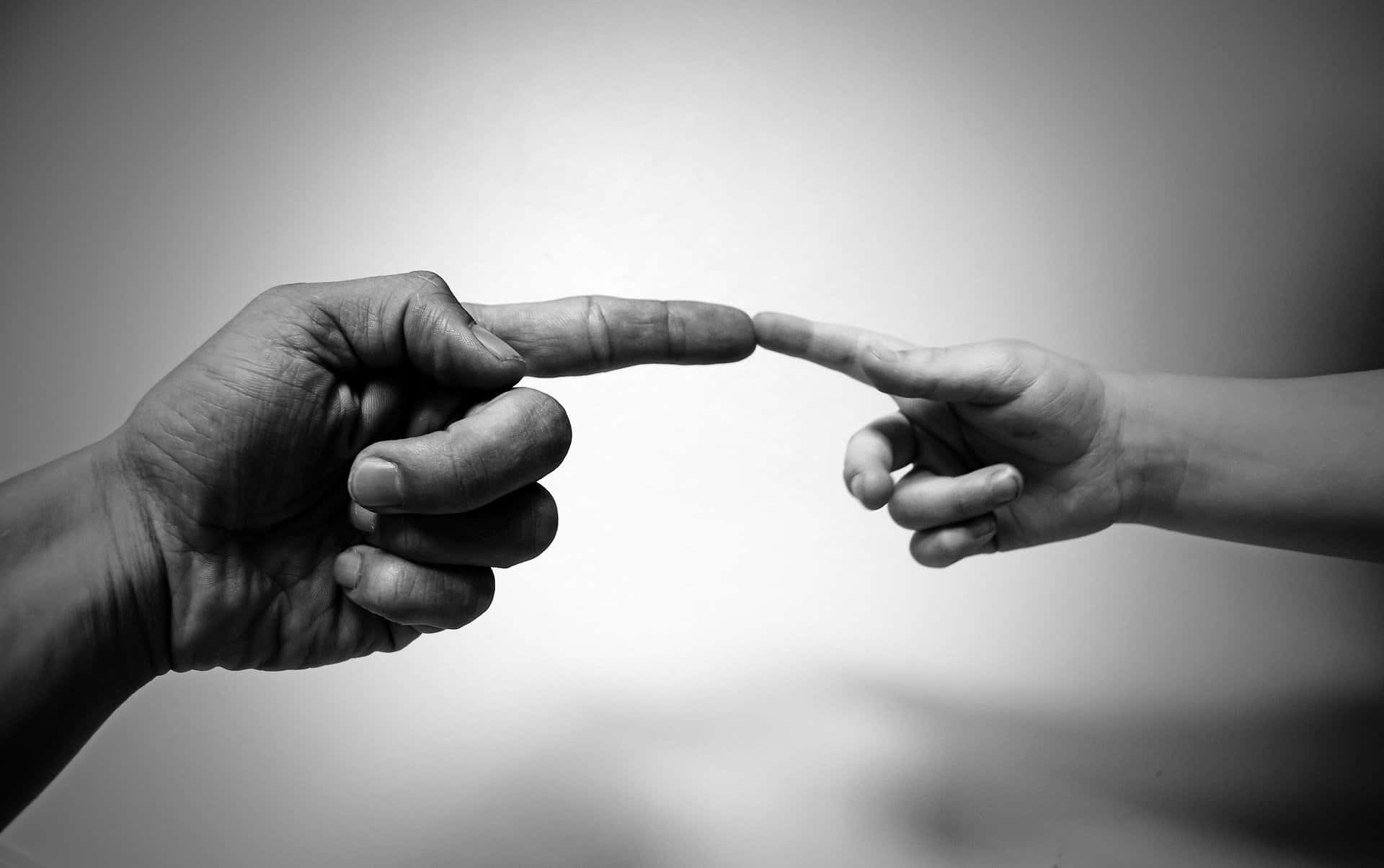 Black And White Photo Of Tangible Touching Of Index Fingers Wallpaper
