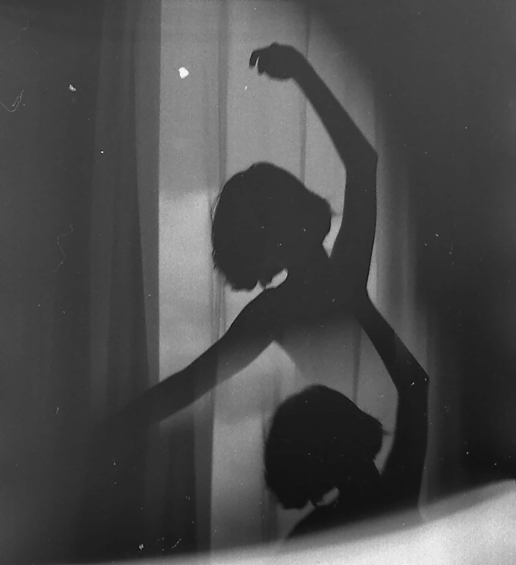 a silhouette of a woman dancing in front of a window