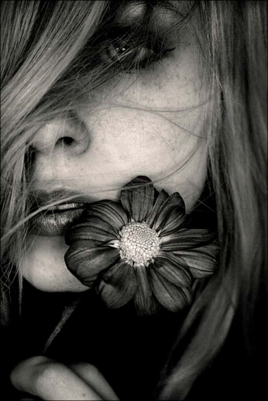 a black and white photo of a woman holding a flower