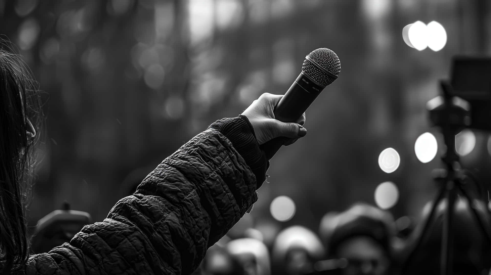 Black And White Protest Scene With A Hand Holding A Microphone For Public Speech Wallpaper