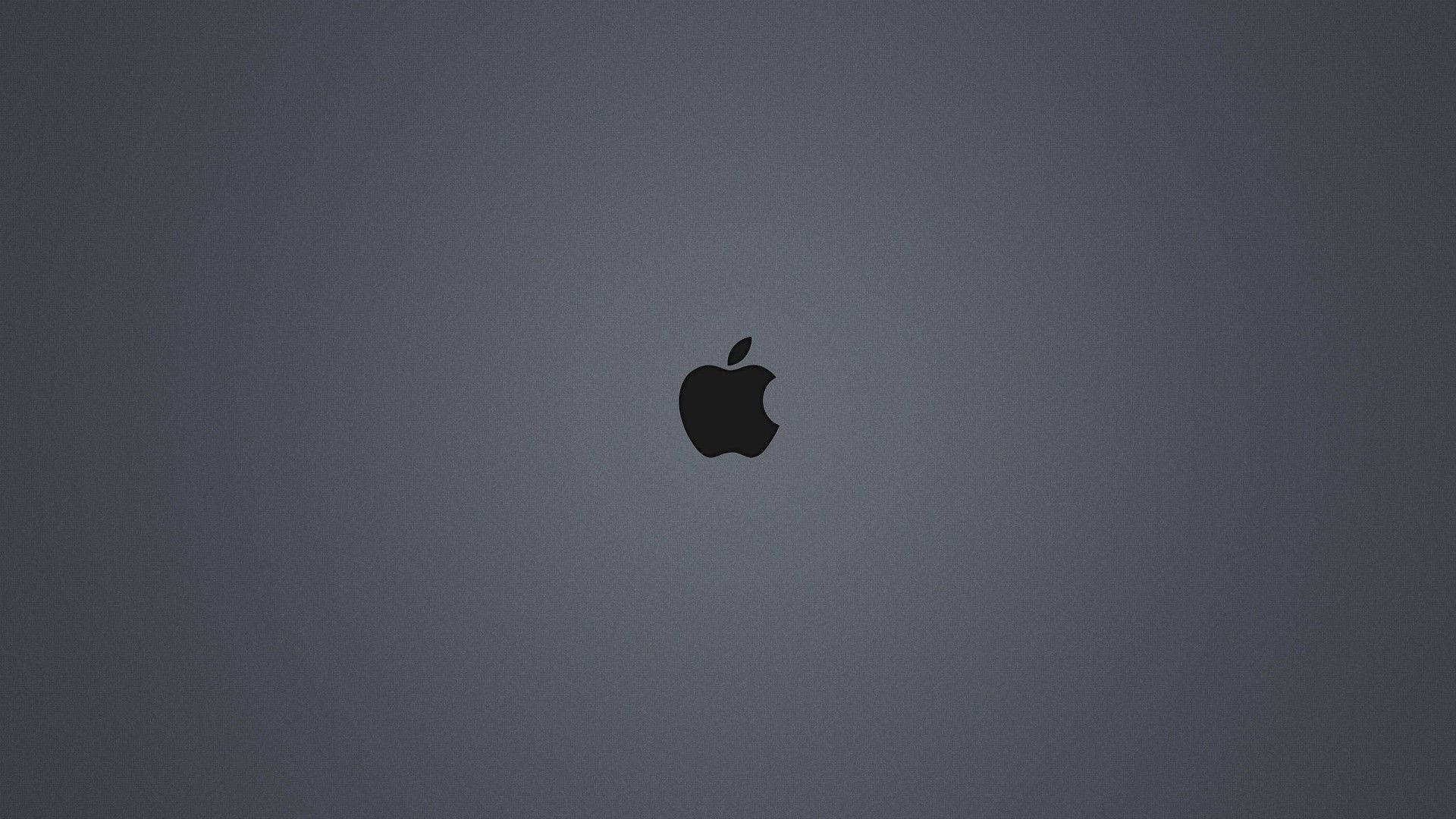 A dark-gray background illuminated by the iconic black Apple logo Wallpaper