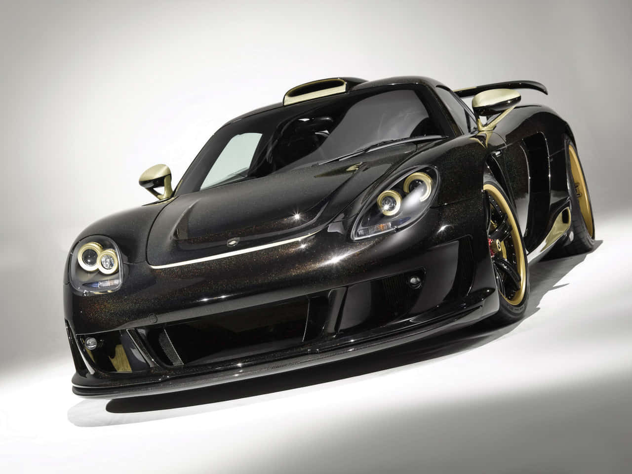 A Black And Gold Sports Car Is Shown In A Studio