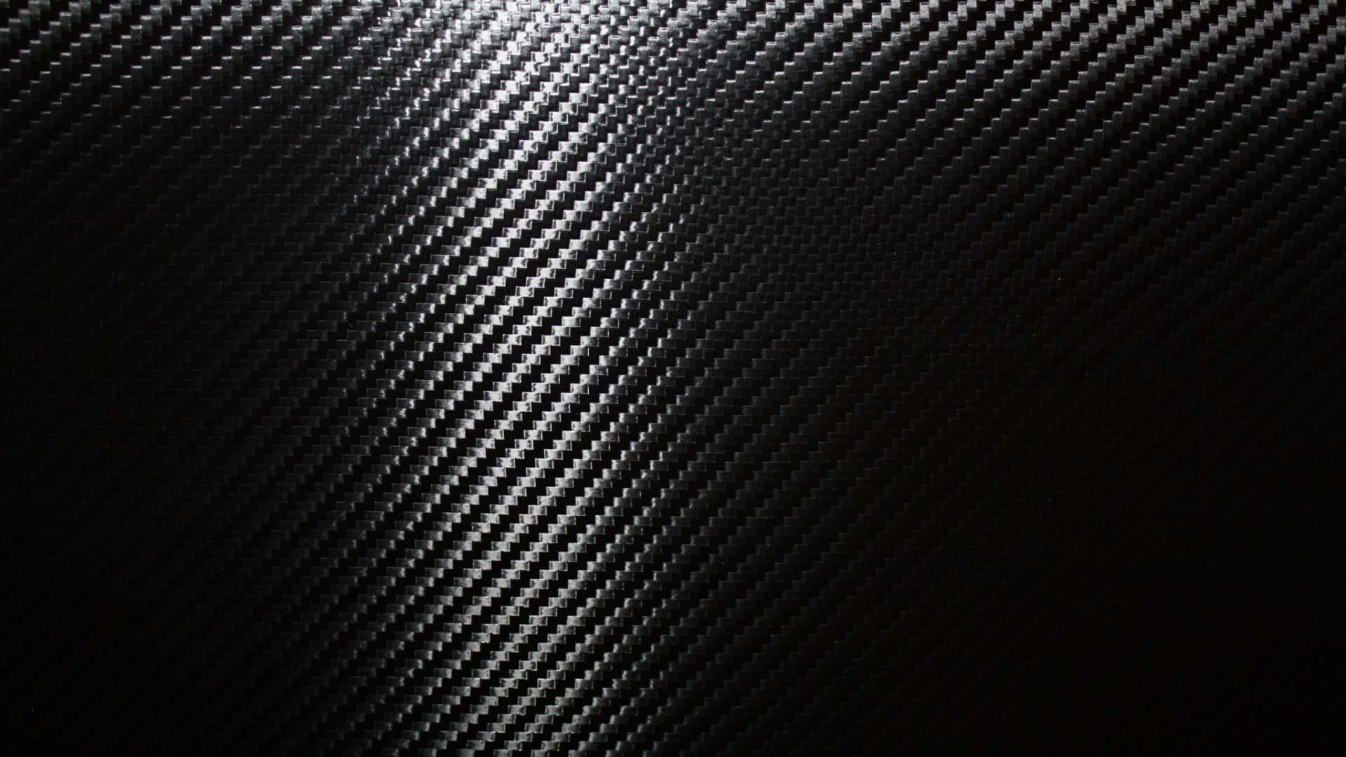 A close-up view of black carbon fiber in a luxurious pattern Wallpaper