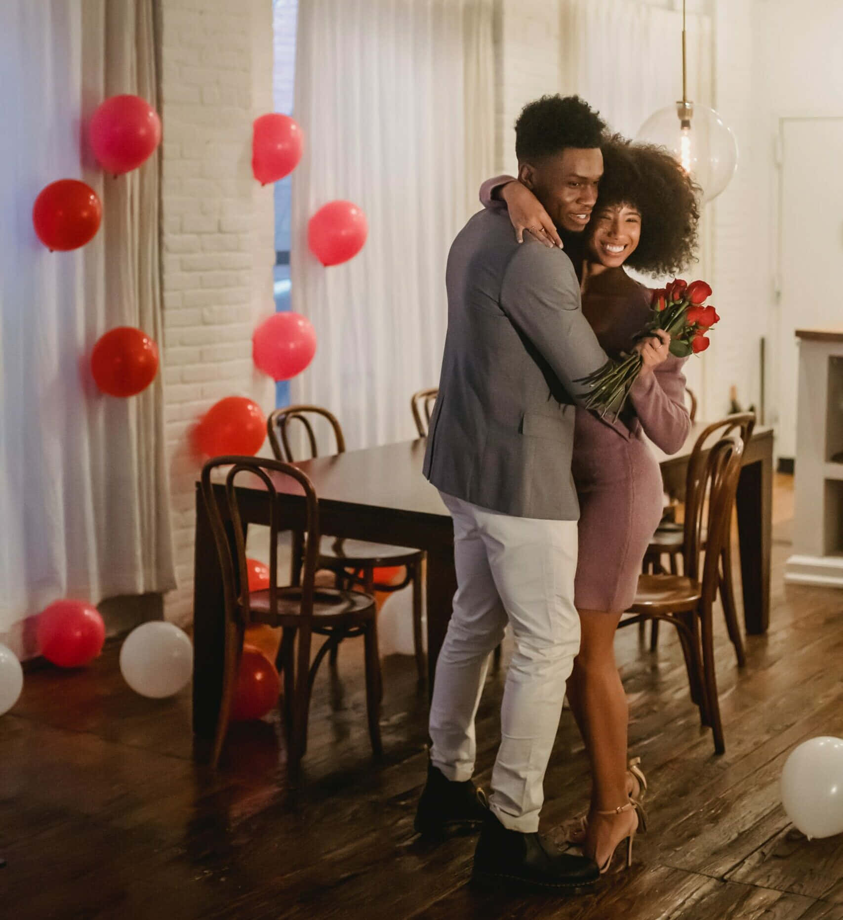 A Couple Hugging In A Living Room With Balloons