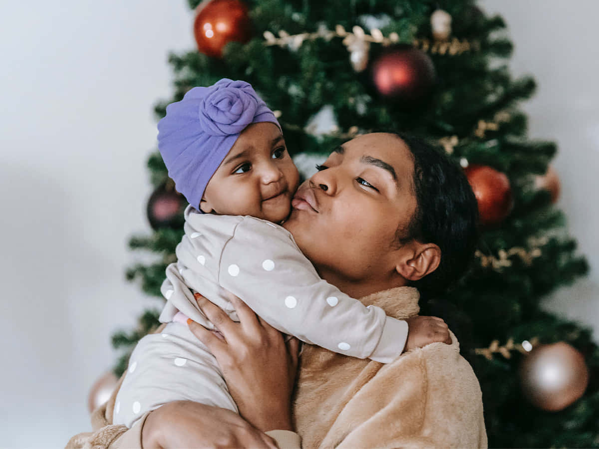 Madrebesando A Su Bebé En Una Fotografía Navideña De Una Familia Negra.