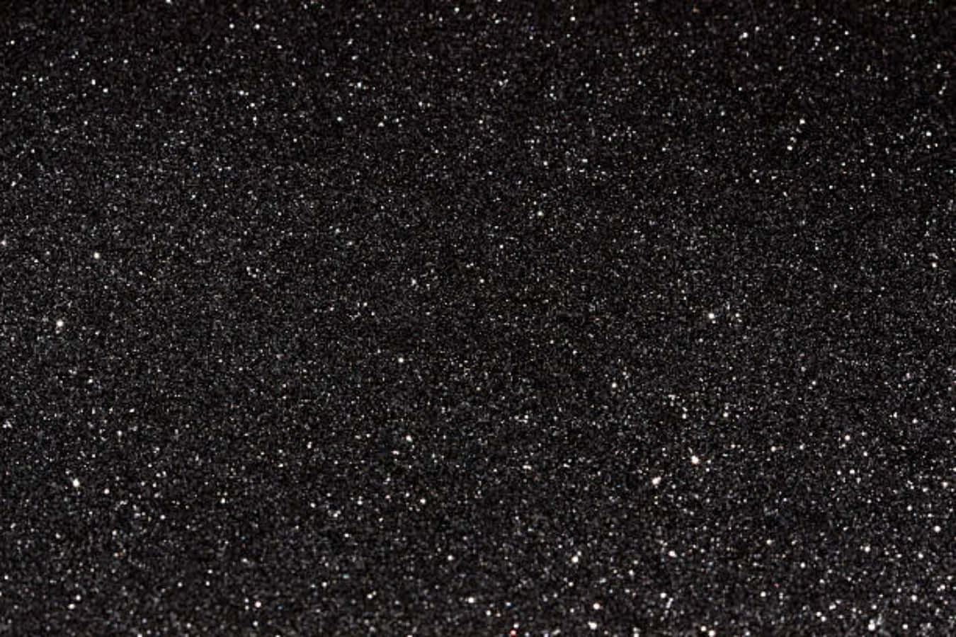 A vibrant sparkle of black glitter swirling and glimmering down a canvas of gray.