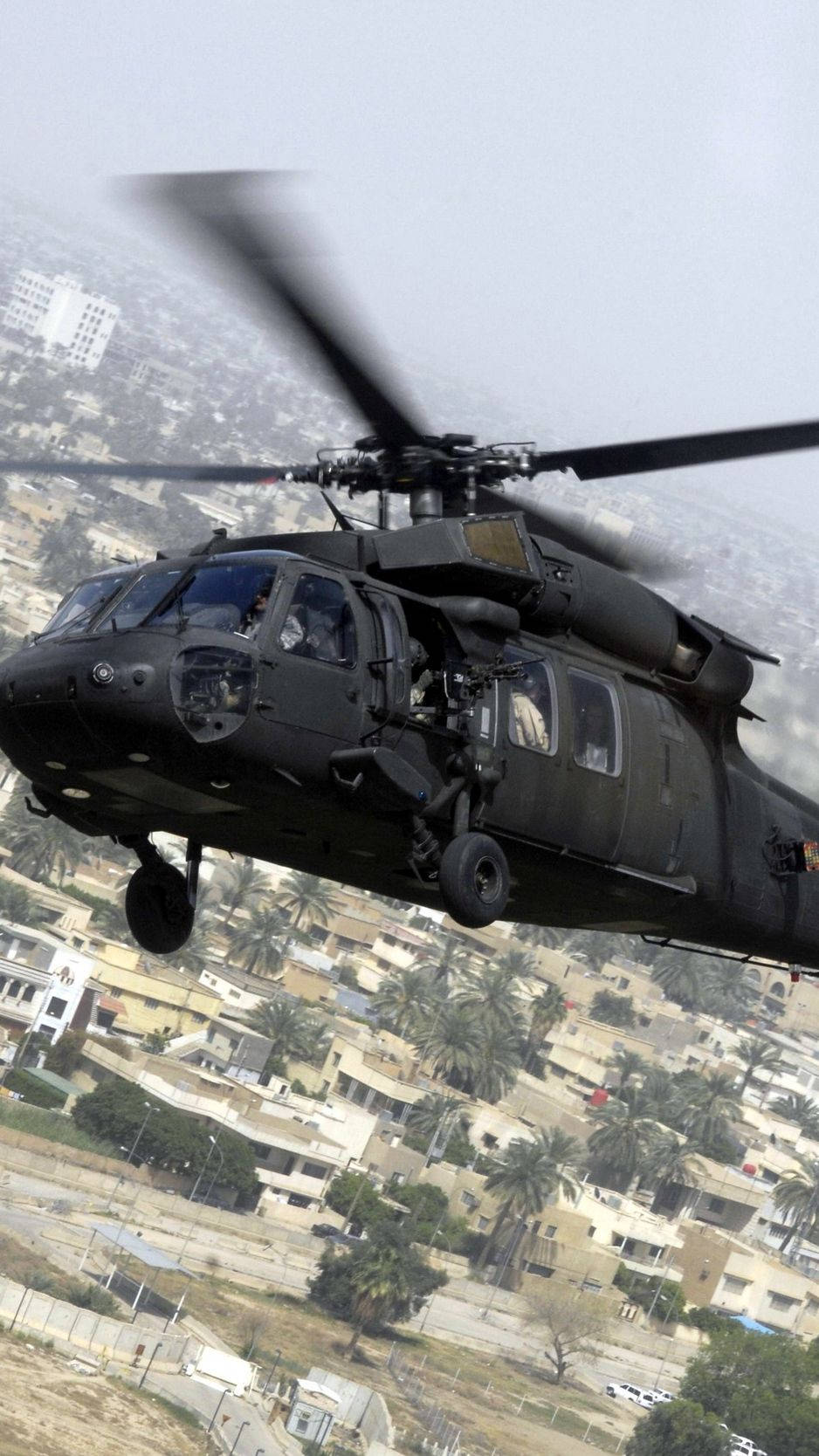 Military Black Hawk Helicopter Soaring Over Landscape Wallpaper