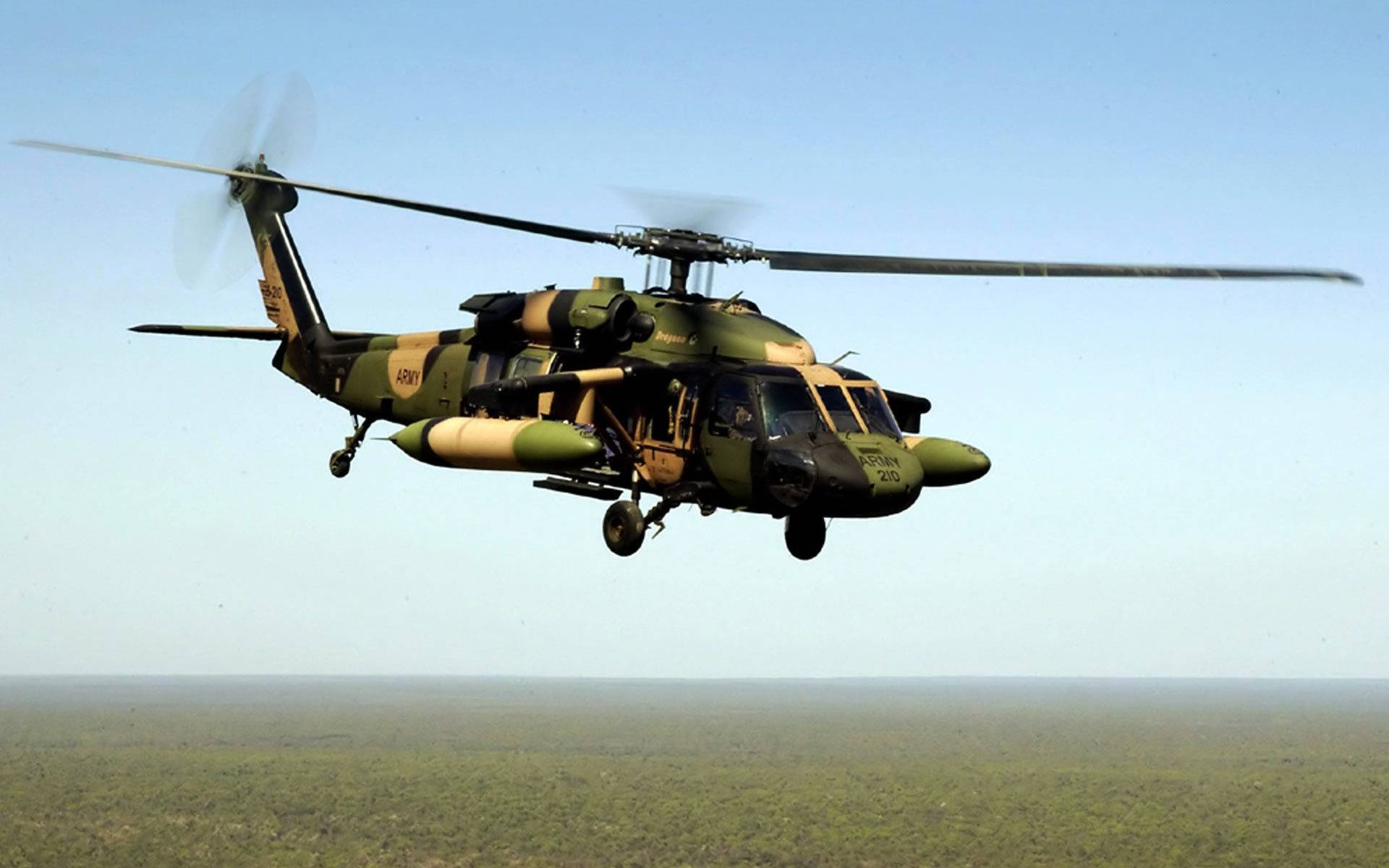 Unhelicóptero Militar Volando Sobre Un Bosque Fondo de pantalla