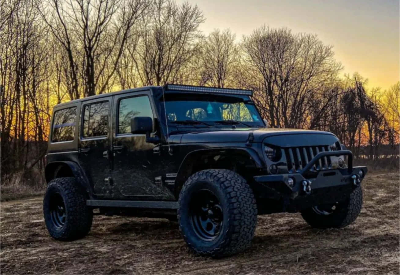 A Black Jeep Parked In The Woods At Sunset