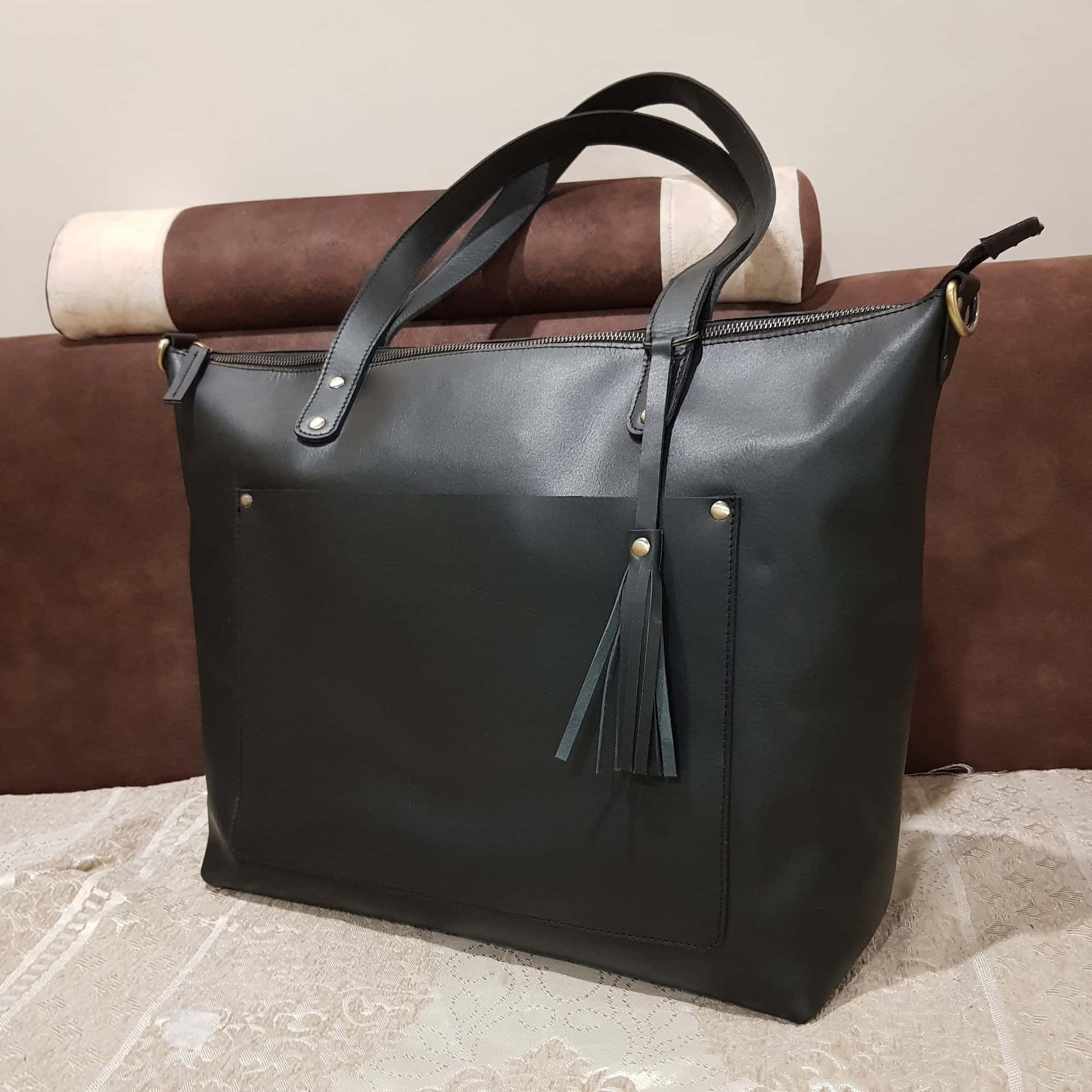 A Black Leather Tote Bag With A Tassel