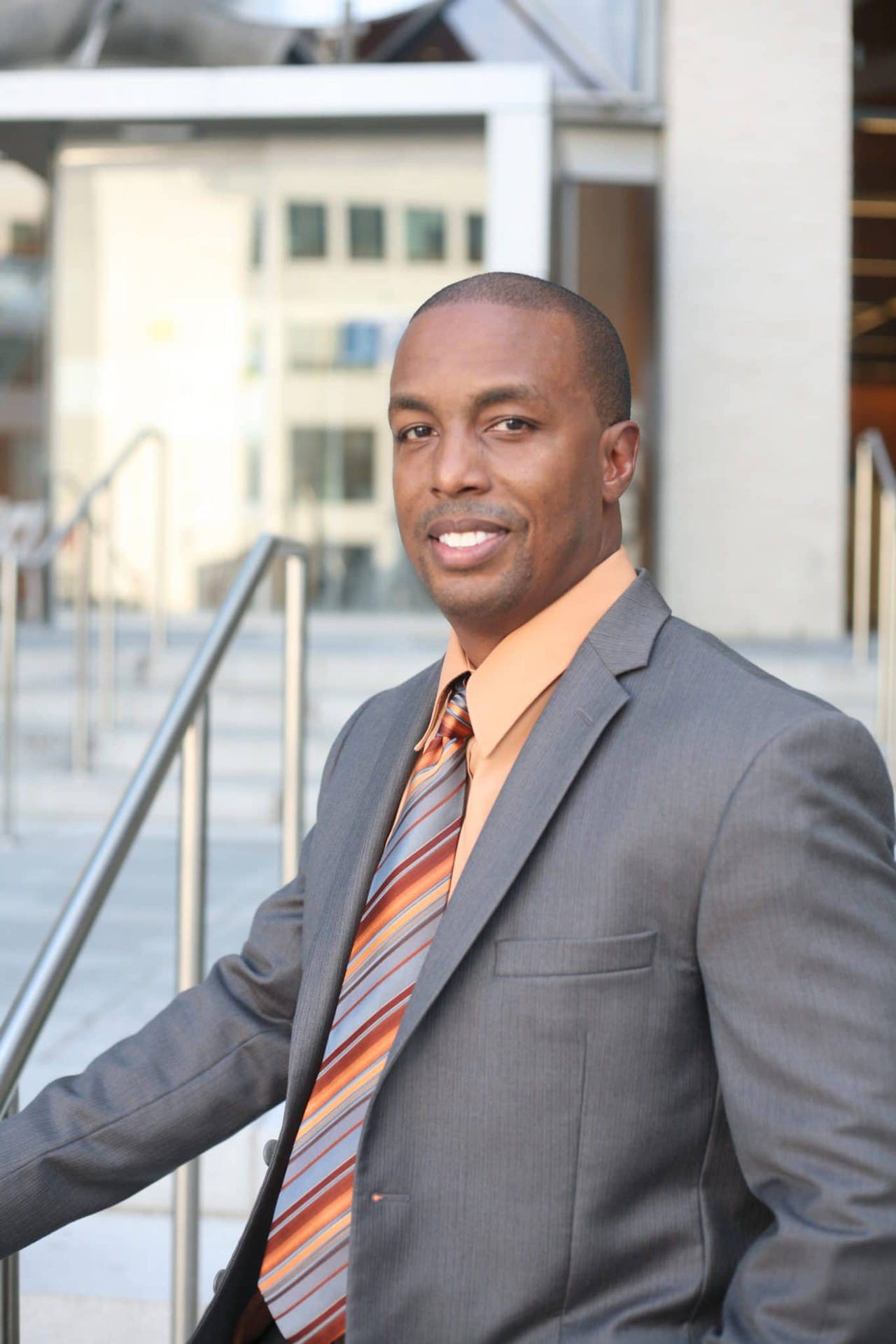Black Man In Orange And Gray Suit Background