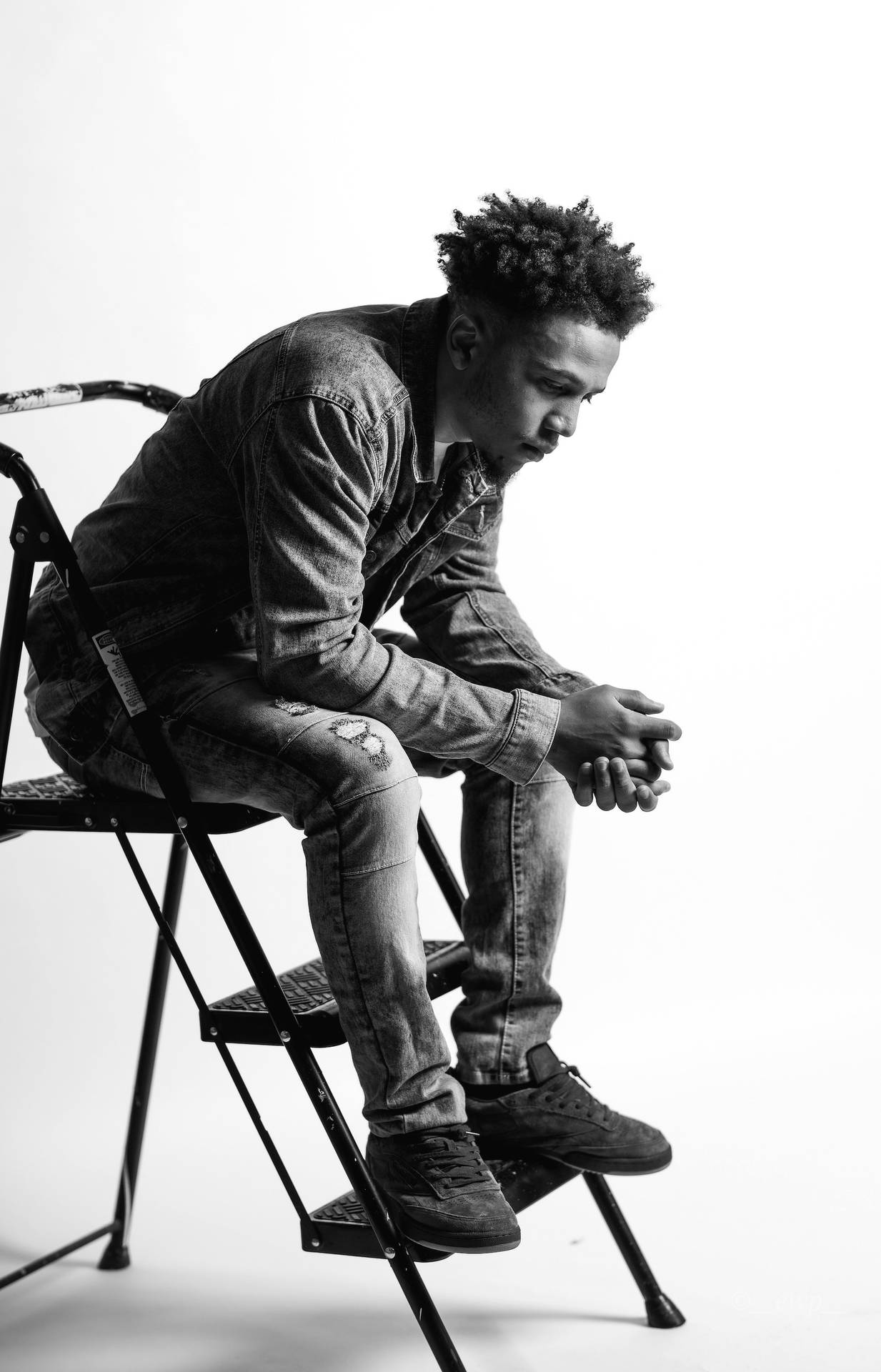 Black Man Sitting On A Stepladder Background