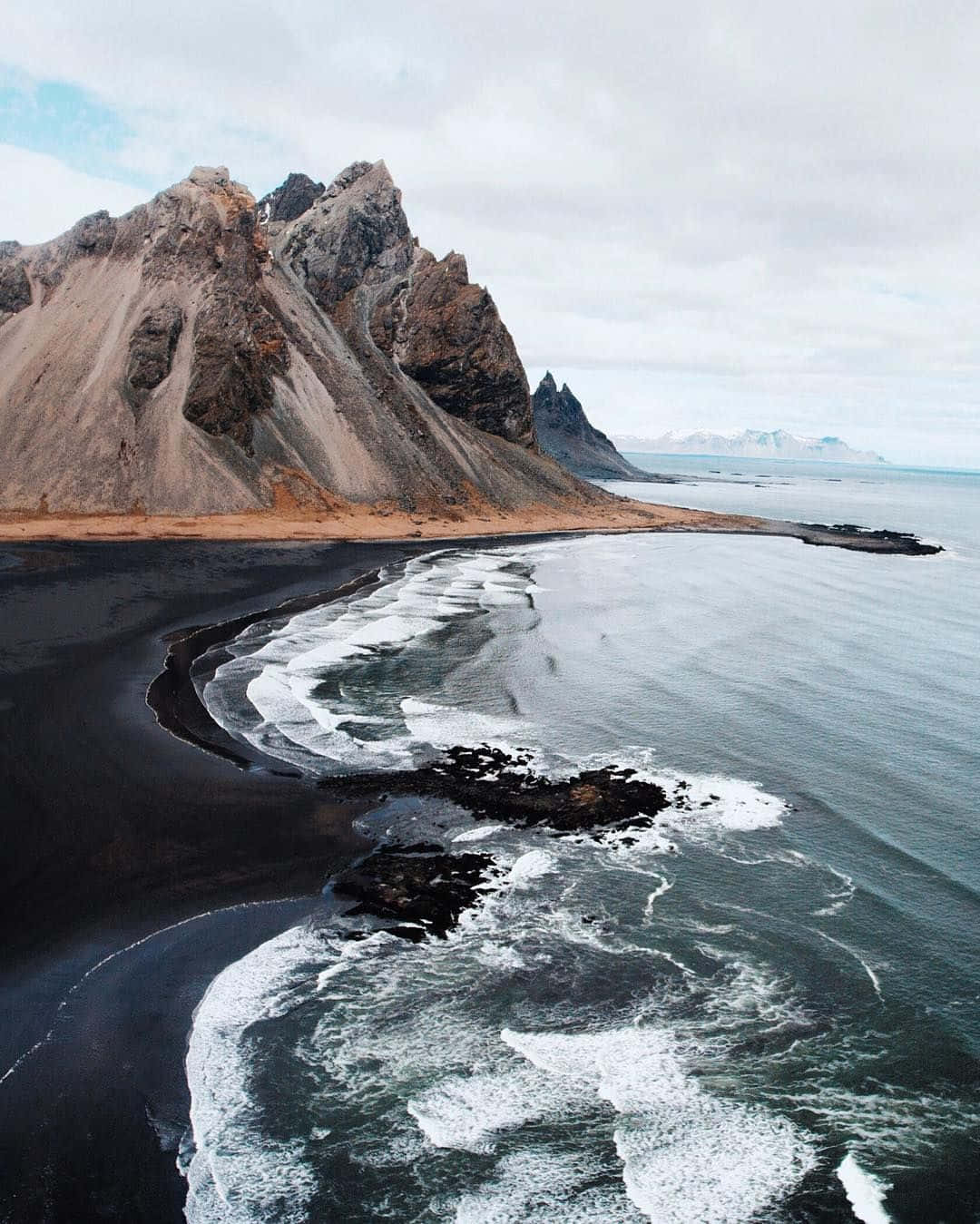 Take a moment to appreciate the beauty of a black sand beach. Wallpaper