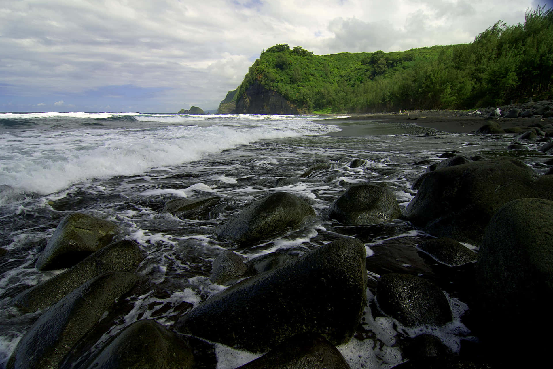 Experience the peaceful beauty of a black sand beach Wallpaper