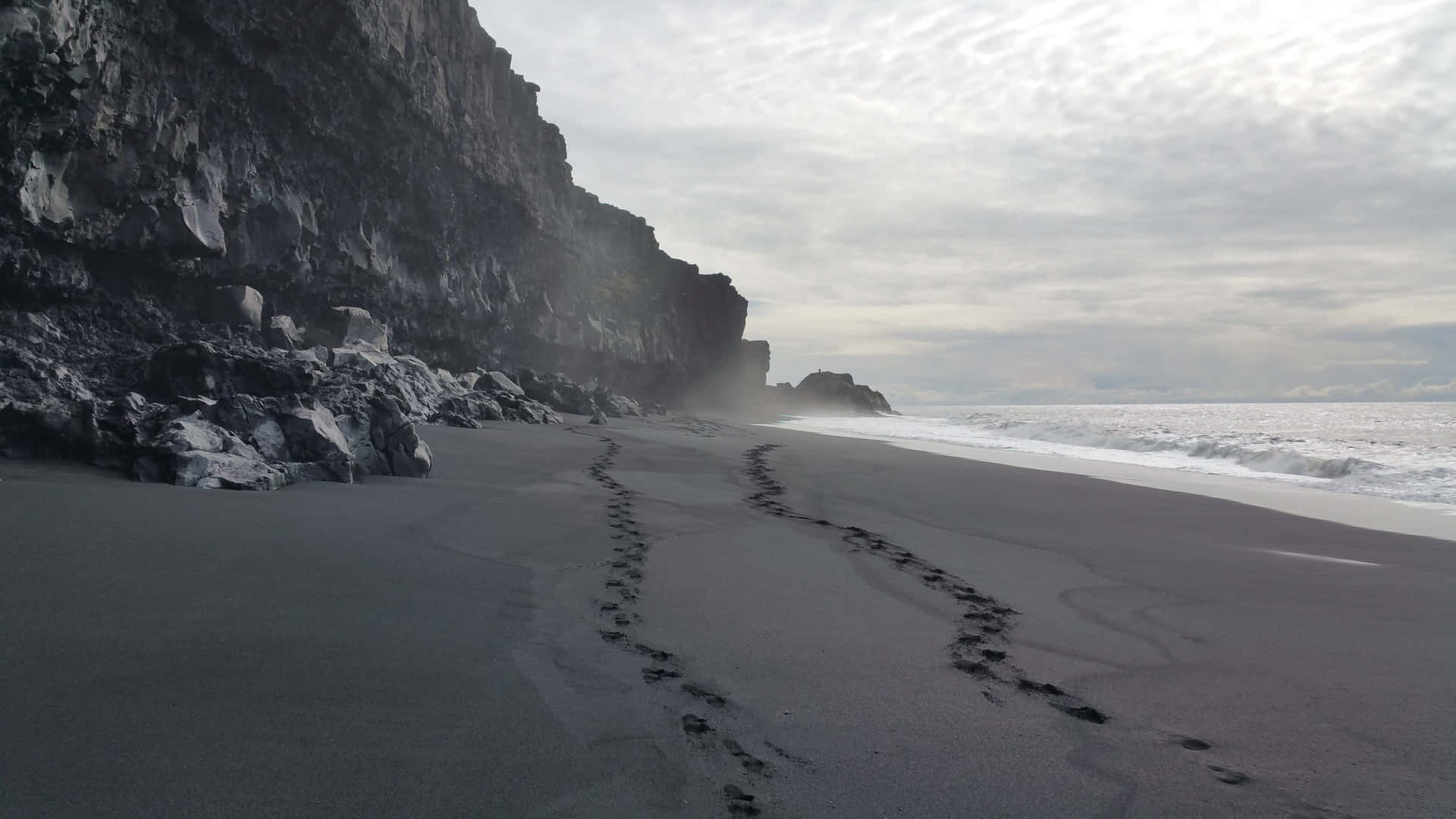 An eye-catching view of a black sand beach on a sunny day. Wallpaper