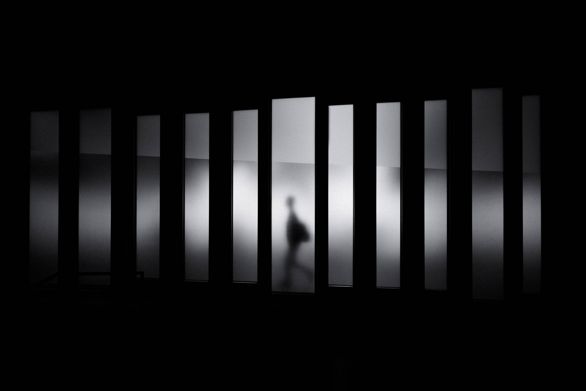 Cool wallpaper of black, blurry, shadow of a person walking in panels. 