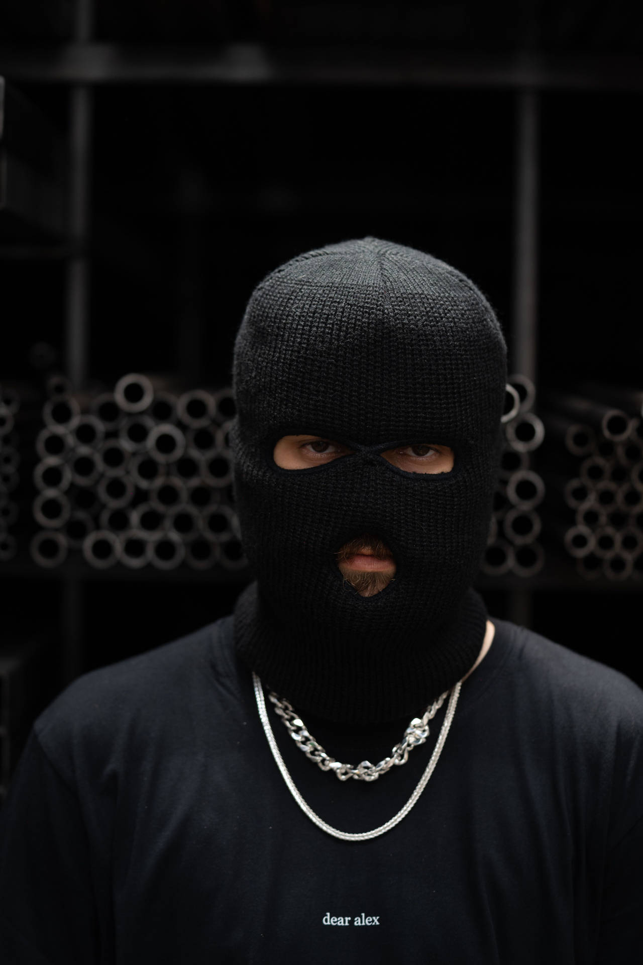 A Man In A Black Mask Standing In Front Of A Rack Wallpaper