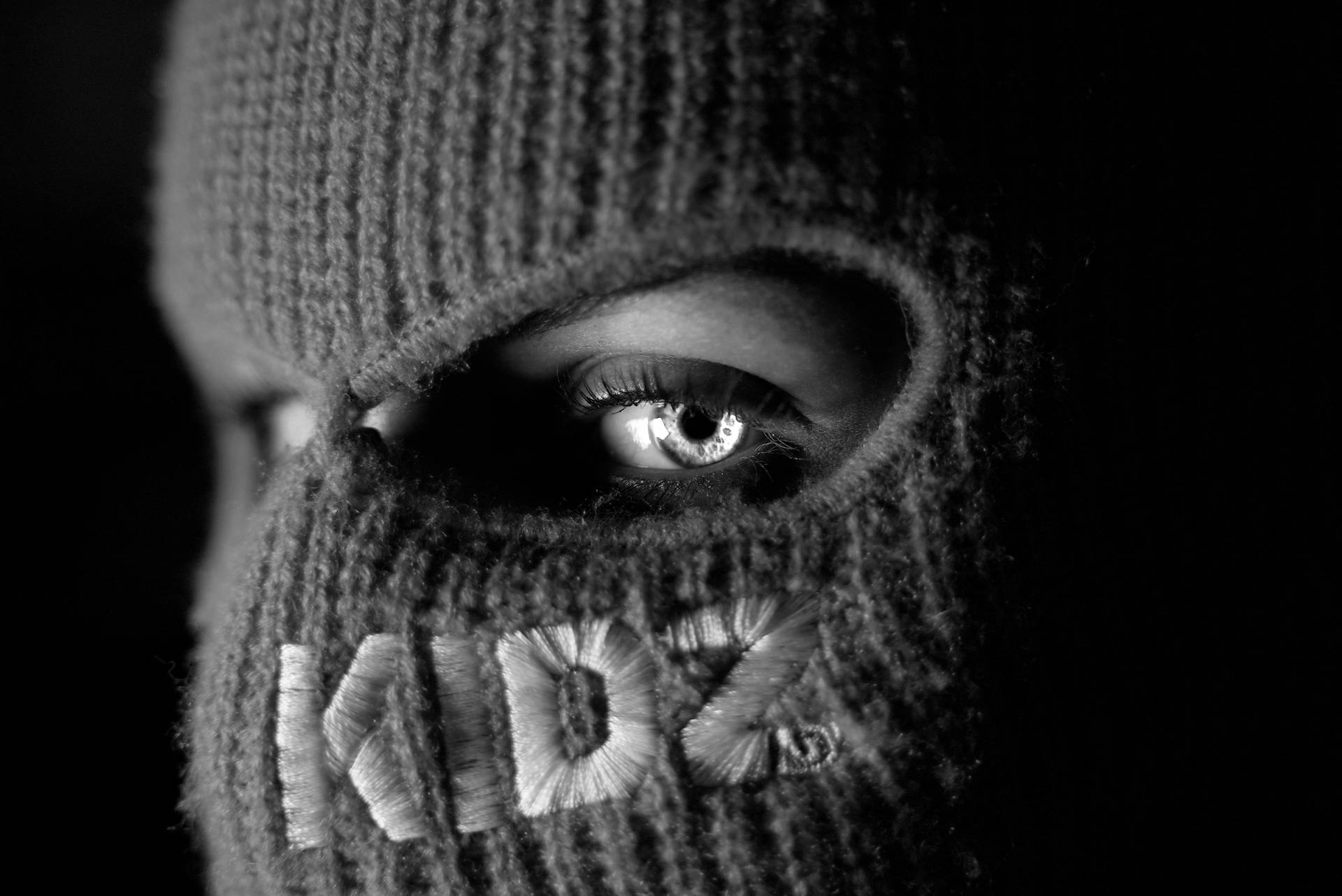Et sort-hvidt foto af en person iført en strikket maske Wallpaper