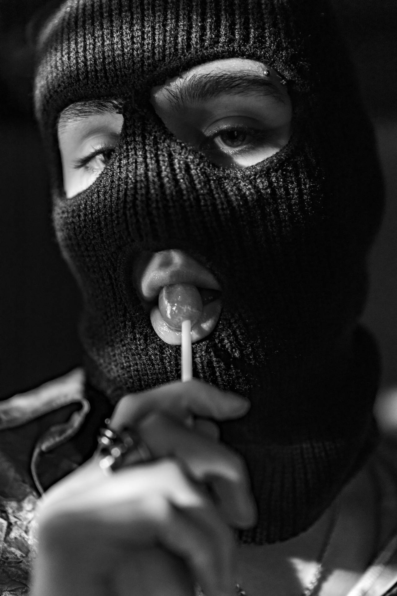 A Man In A Black Mask Is Chewing A Lollipop Wallpaper