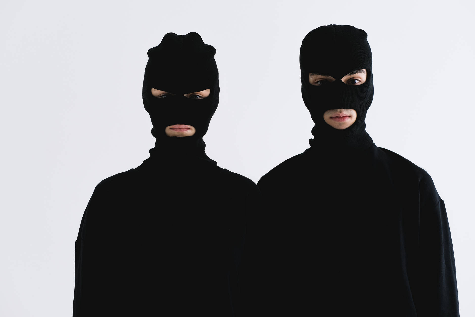 Two Men In Black Masks Standing Next To Each Other Wallpaper