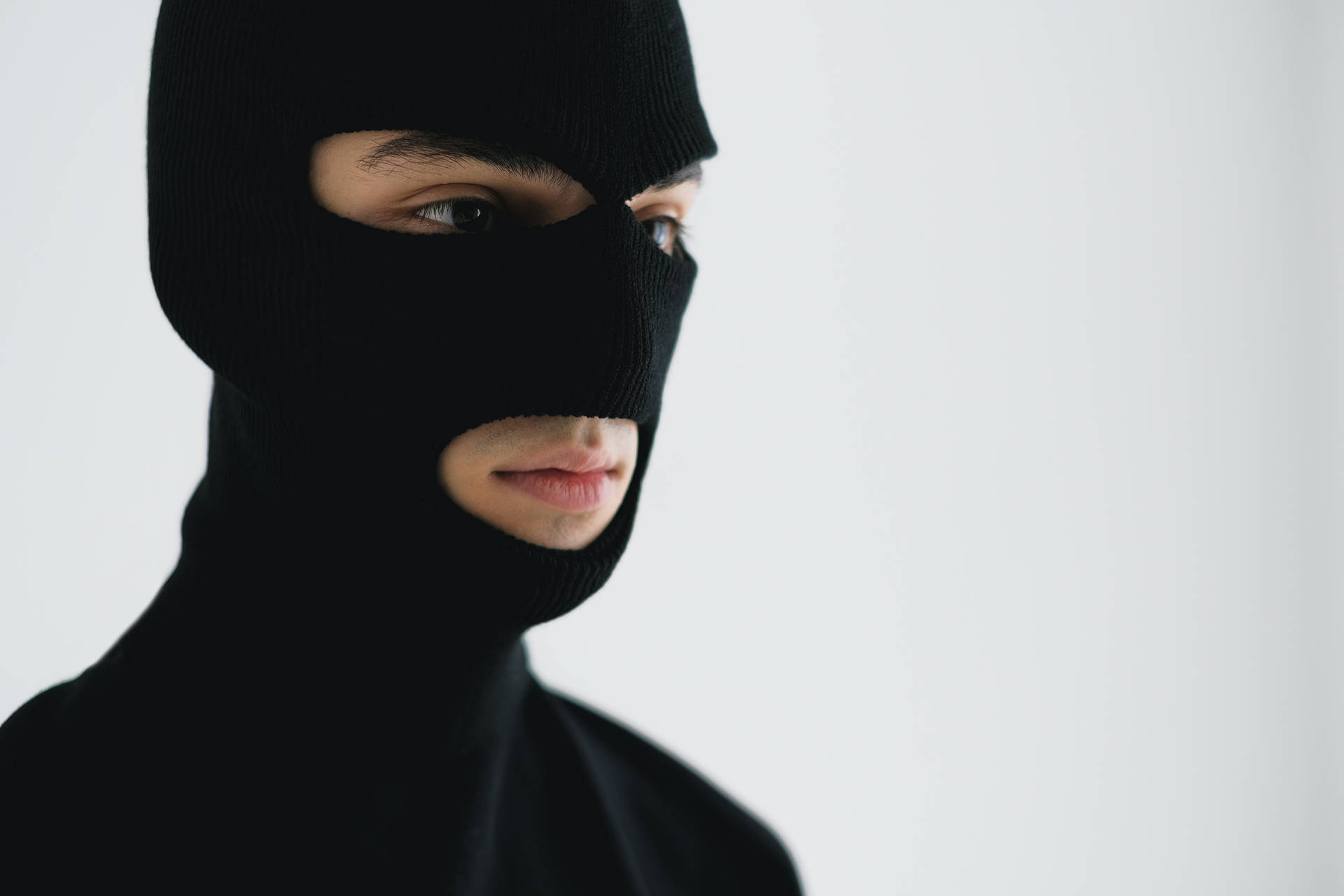A Man In A Black Mask Is Looking At The Camera Wallpaper
