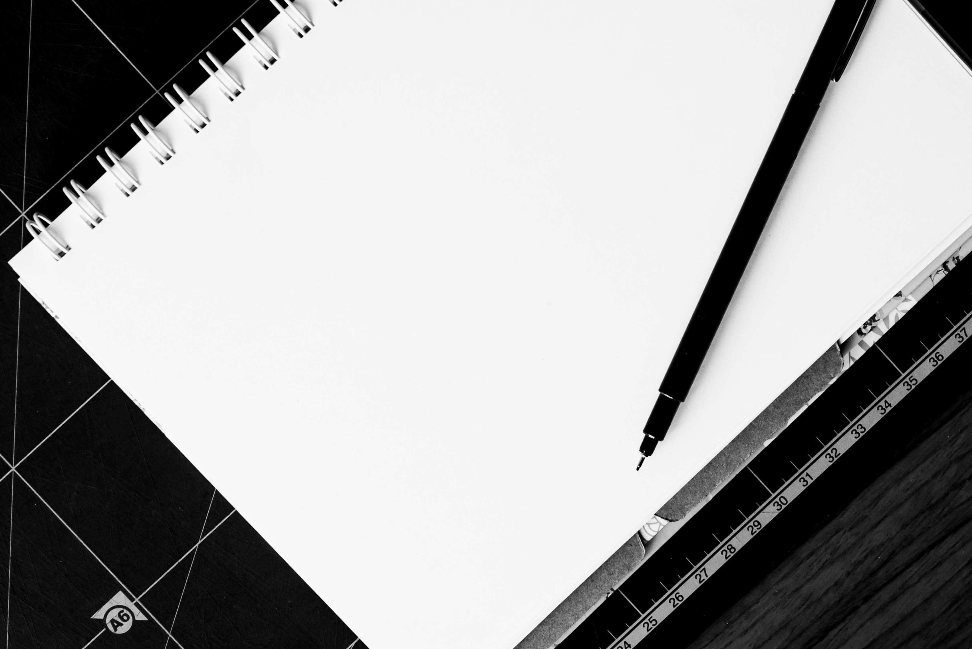 A Black And White Photo Of A Notebook And A Pen