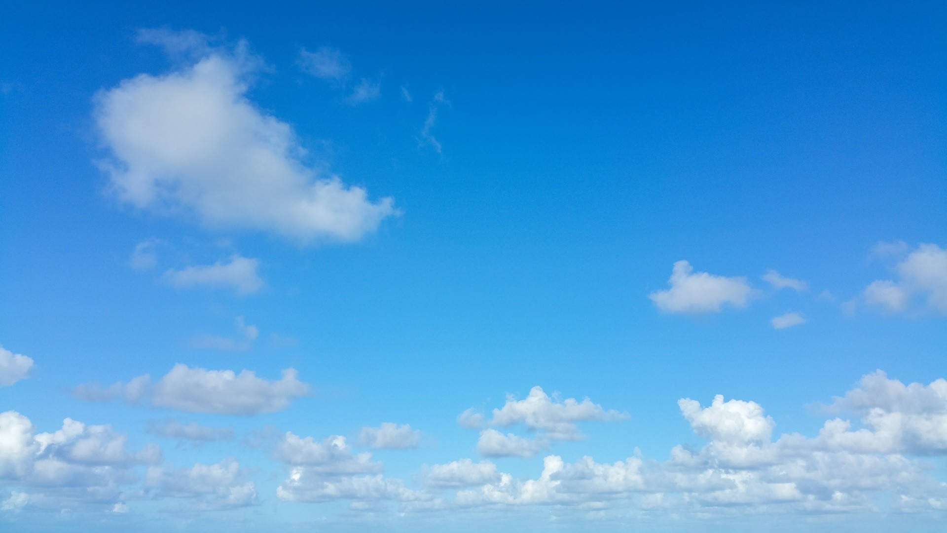 Blå og hvide Altocumulus-skyer synes at røre havet. Wallpaper