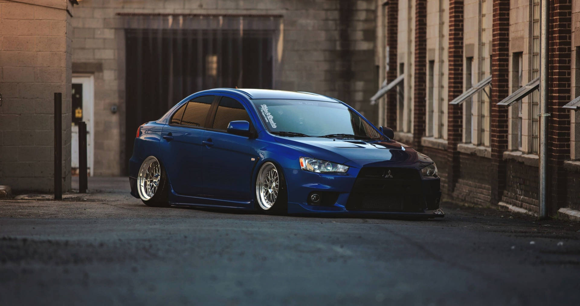 A Brilliant Blue Jdm Mitsubishi Evo Parked in Front of a Building Wallpaper