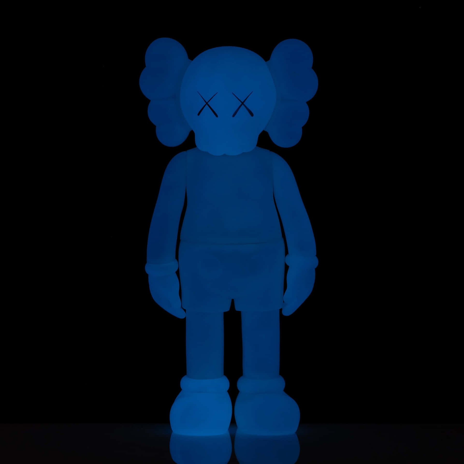 Blue Kaws Figure Standing Against Black Background Wallpaper