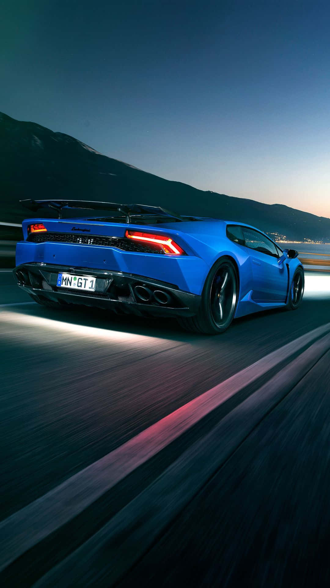 The Blue Lamborghini Huracan Is Driving Down The Road At Night Wallpaper