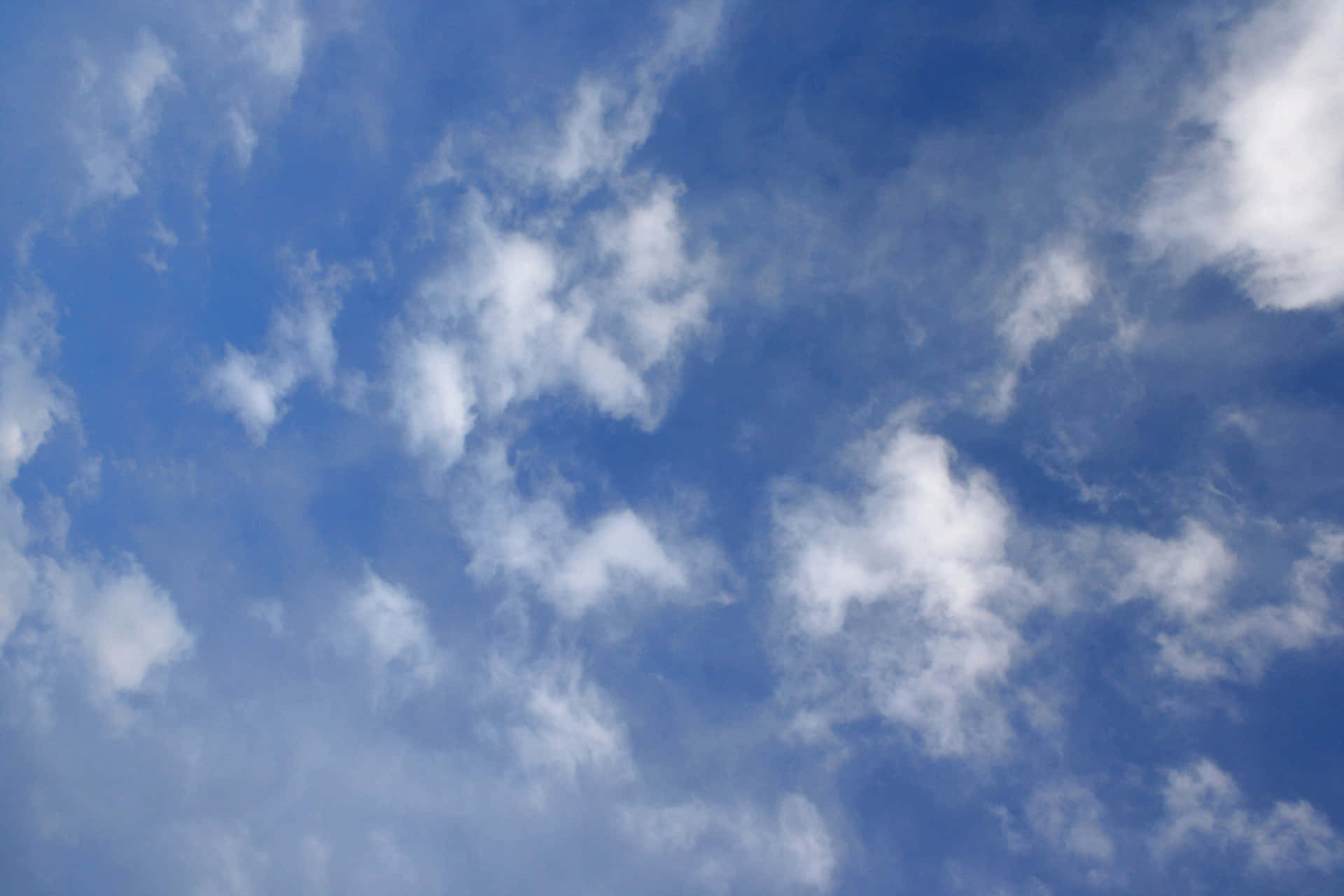 A bright blue sky, scattered with cottony clouds Wallpaper
