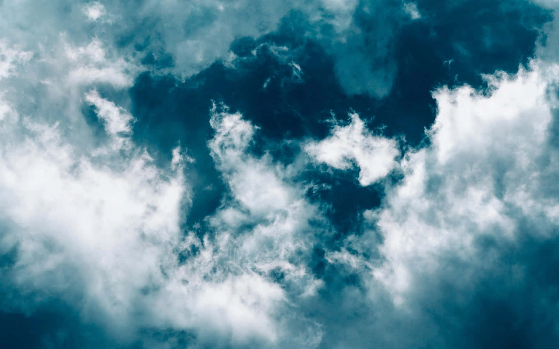 Uncielo Azul Con Nubes Y Un Avión Volando Sobre Él.