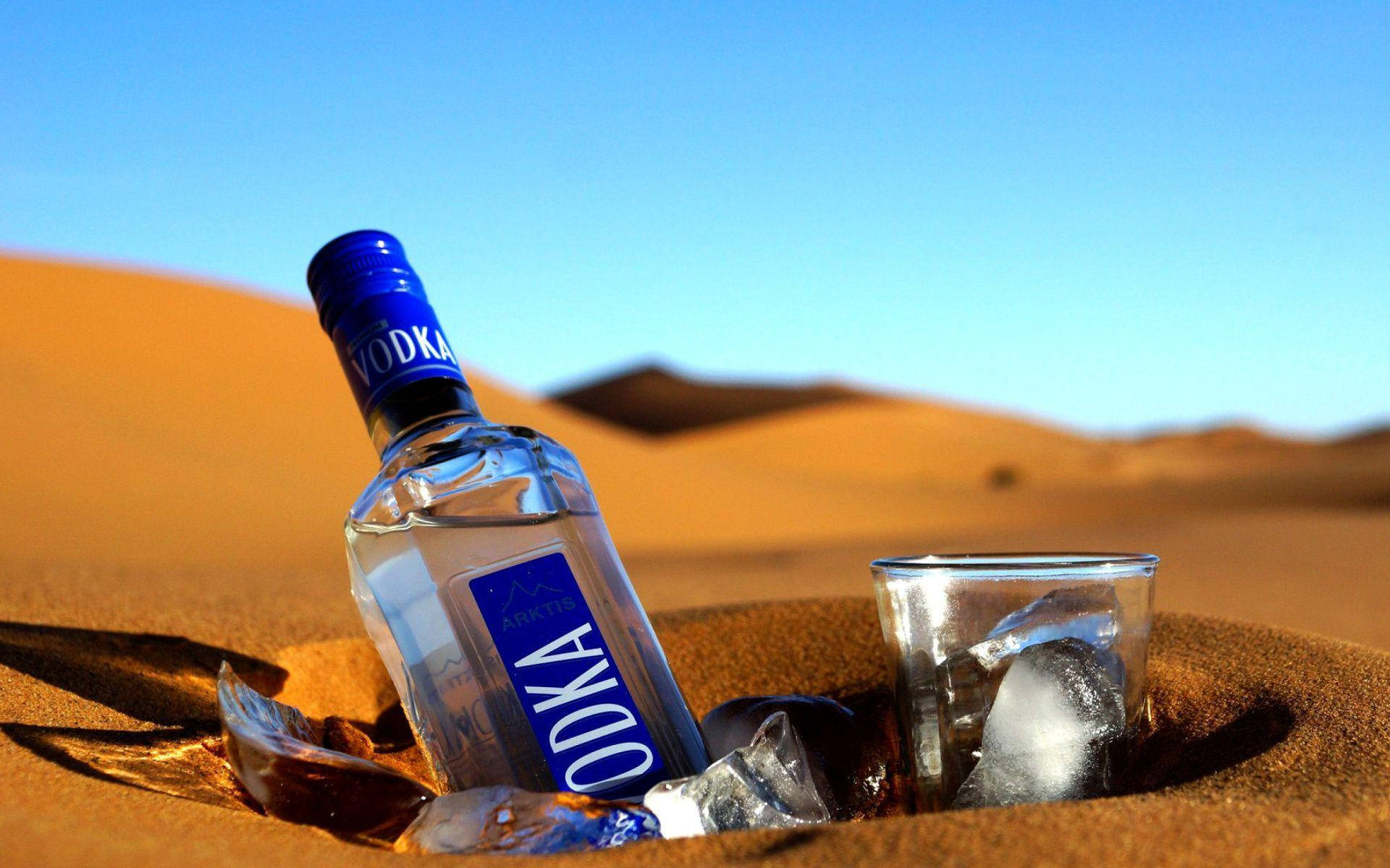 Blue Vodka Bottle And Glass On Desert Sand Wallpaper