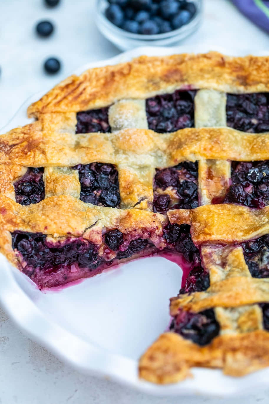 Sweet blueberry pie with fresh, juicy blueberries oozing out of a golden, flaky crust. Wallpaper