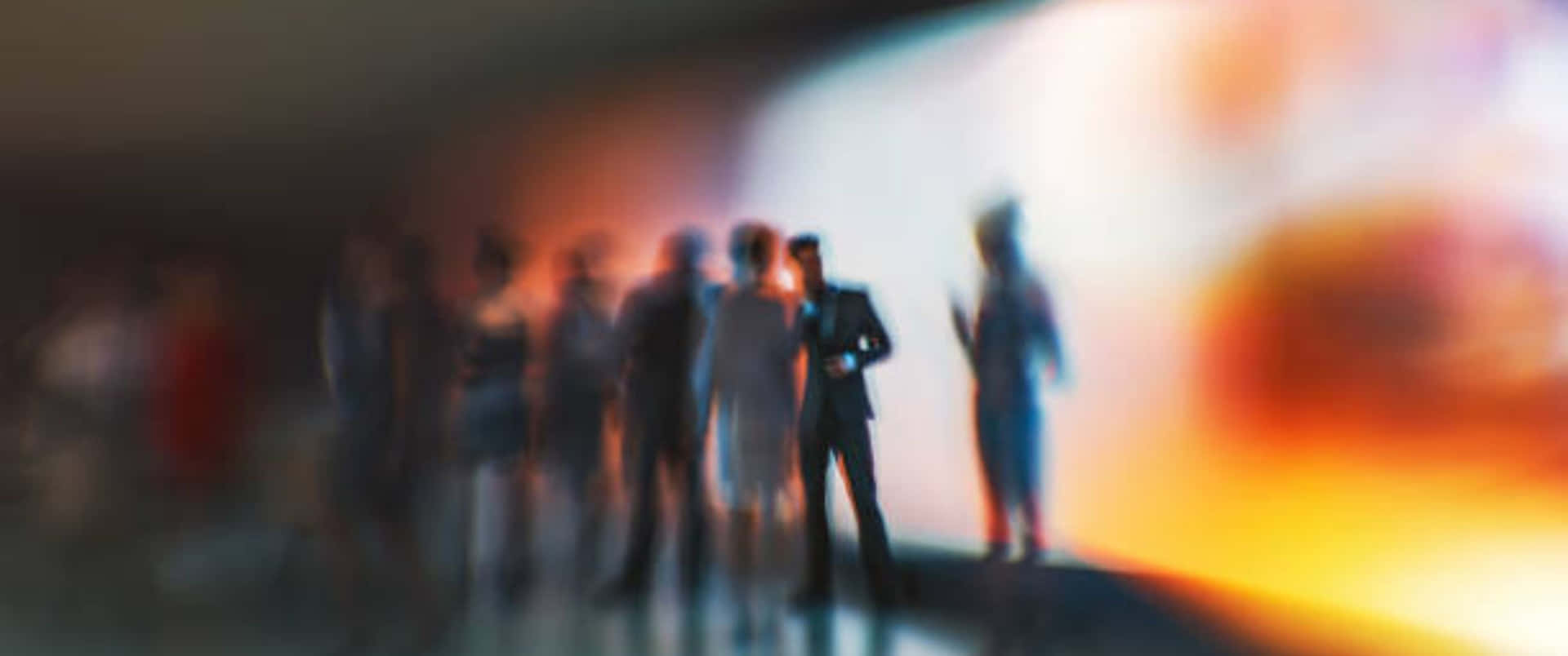Blurred People Standing In Front Of A Screen