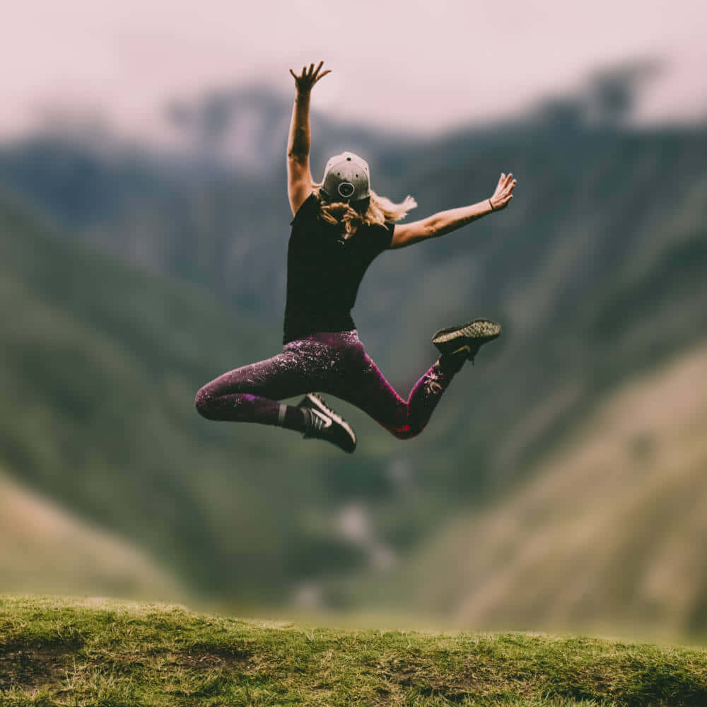 Blurry Background Woman Jumping On A Mountain 1000 x 1000 Background