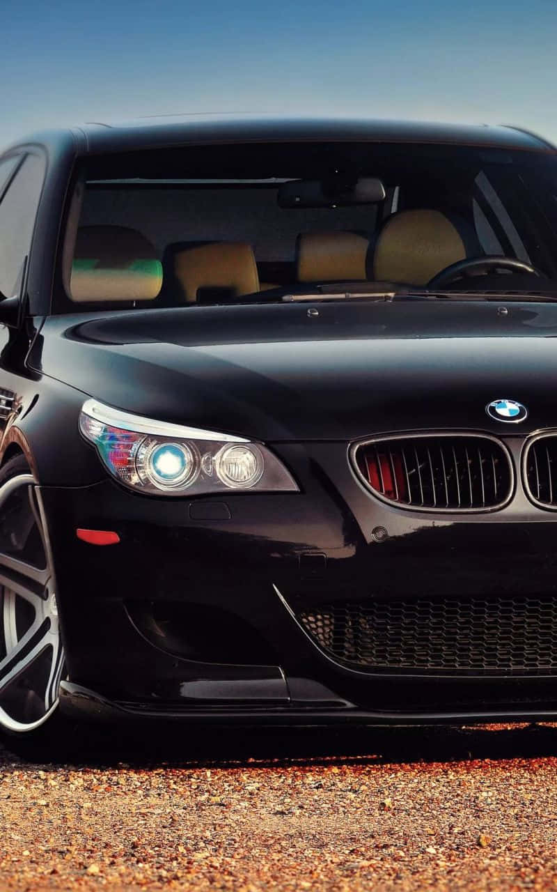 En sort BMW M er fremhævet sammen med en iPhone. Wallpaper