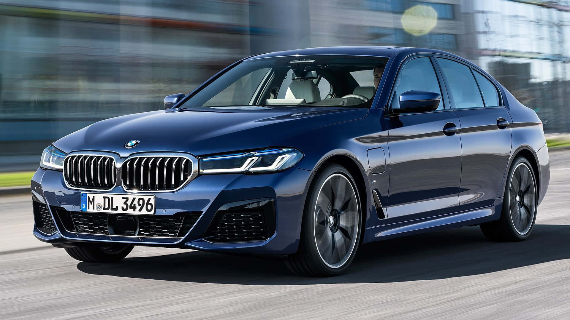 Den 2020 BMW 5-serie sedan kører ned ad gaden. Wallpaper