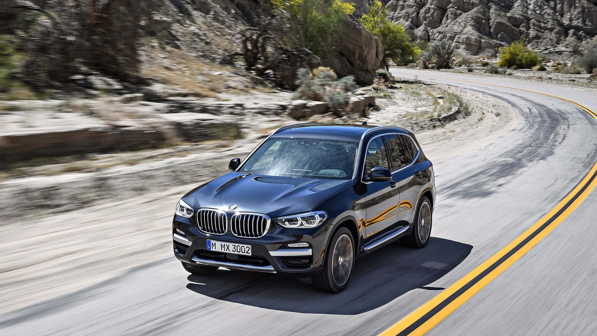 BMW X3 gliding on a scenic highway Wallpaper