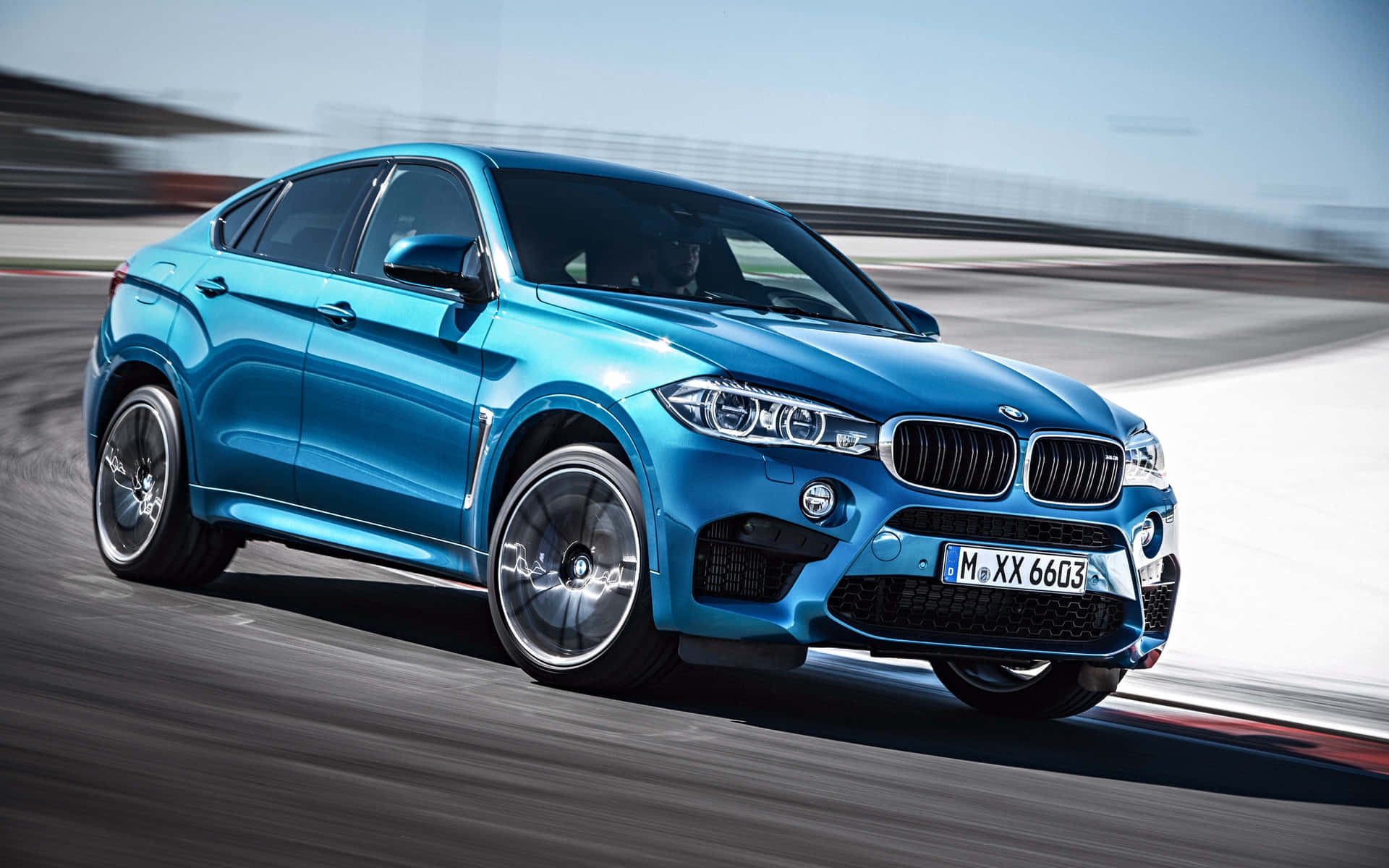 The Blue Bmw X6 Is Driving On A Track