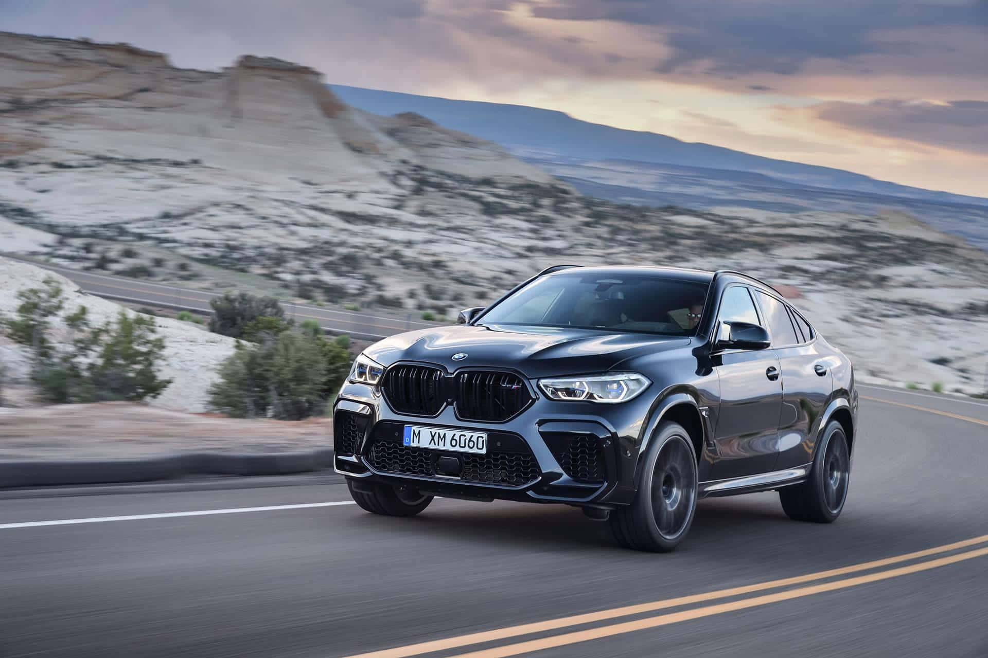The Bmw X6 Is Driving Down A Mountain Road