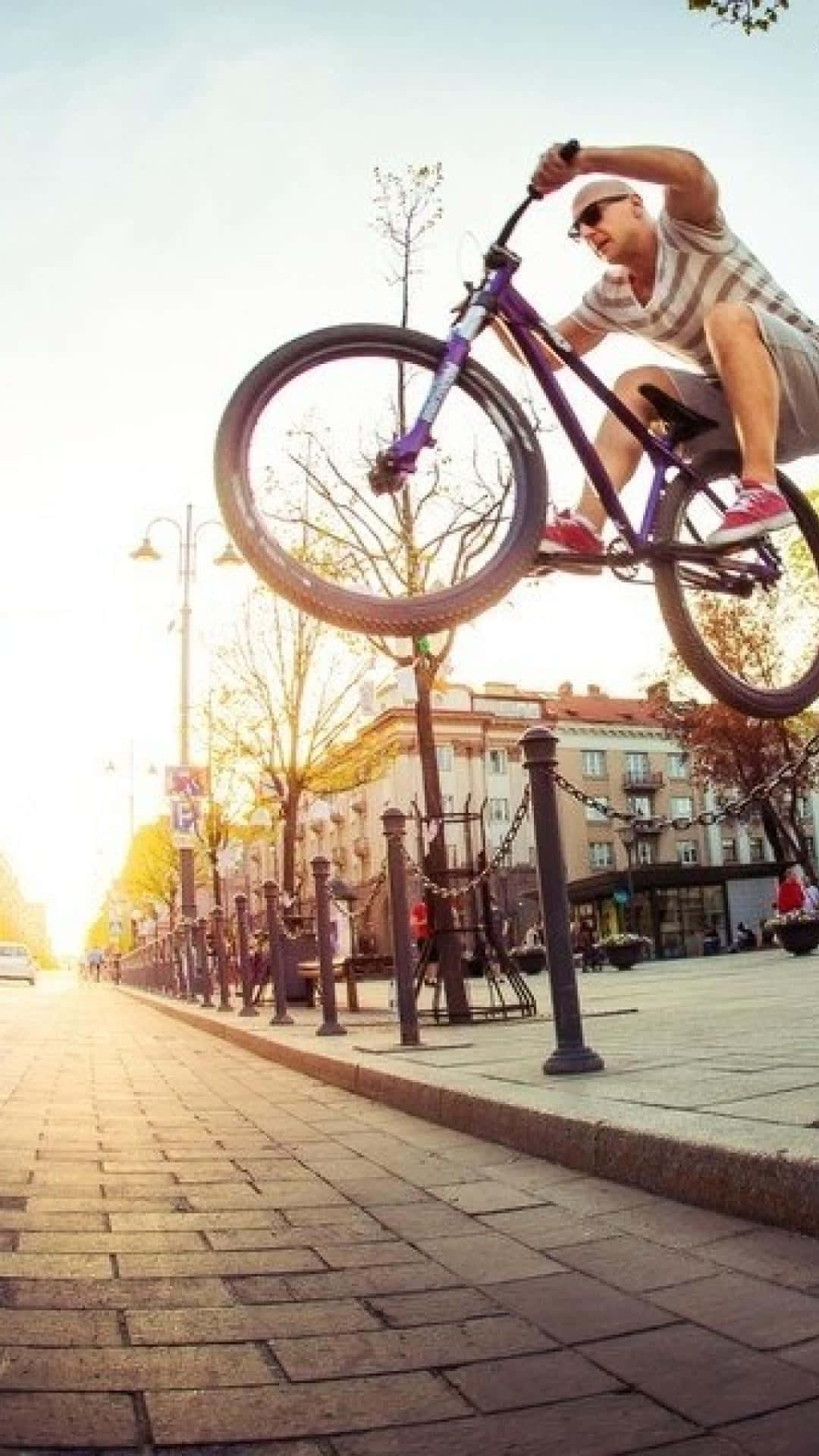 A Man Doing A Bike Trick In The City Wallpaper