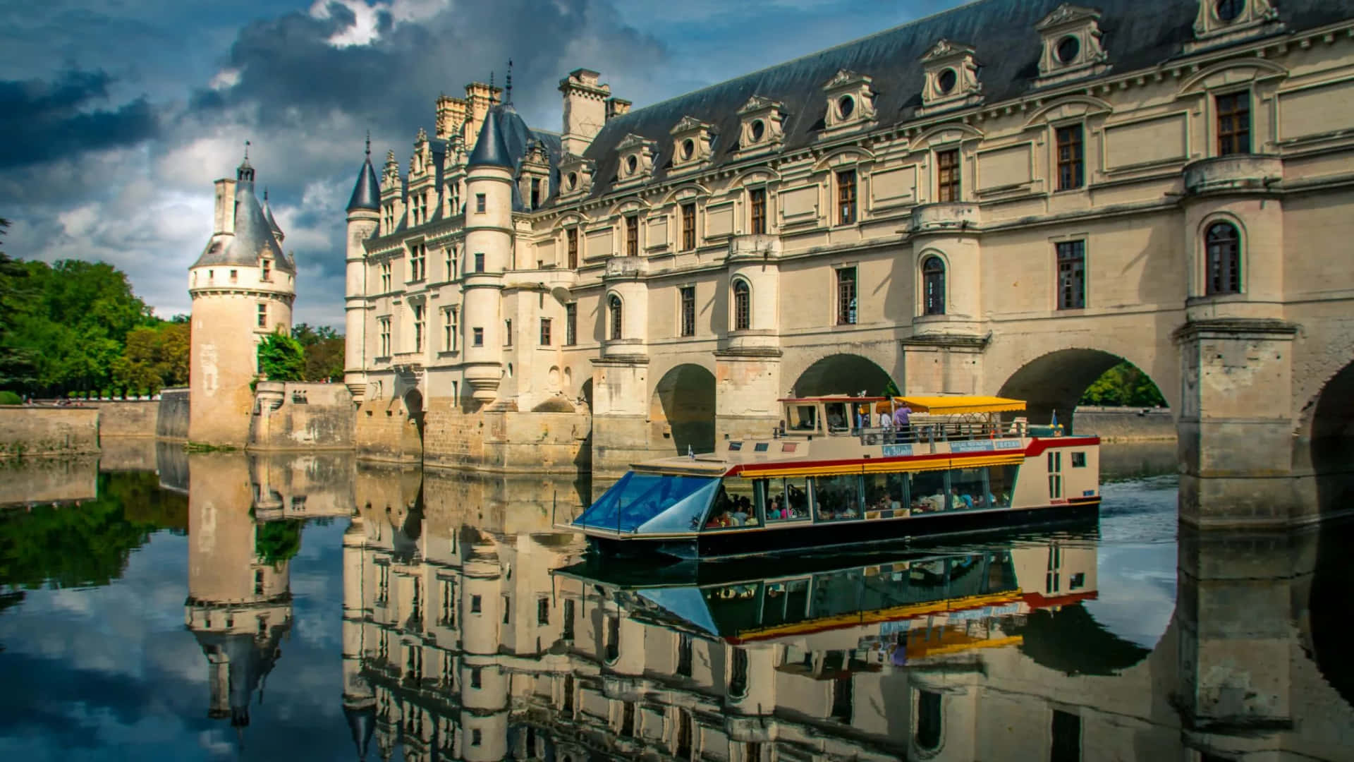 Scenic View of a Boat Passing under the Historic Chenonceau Castle Wallpaper