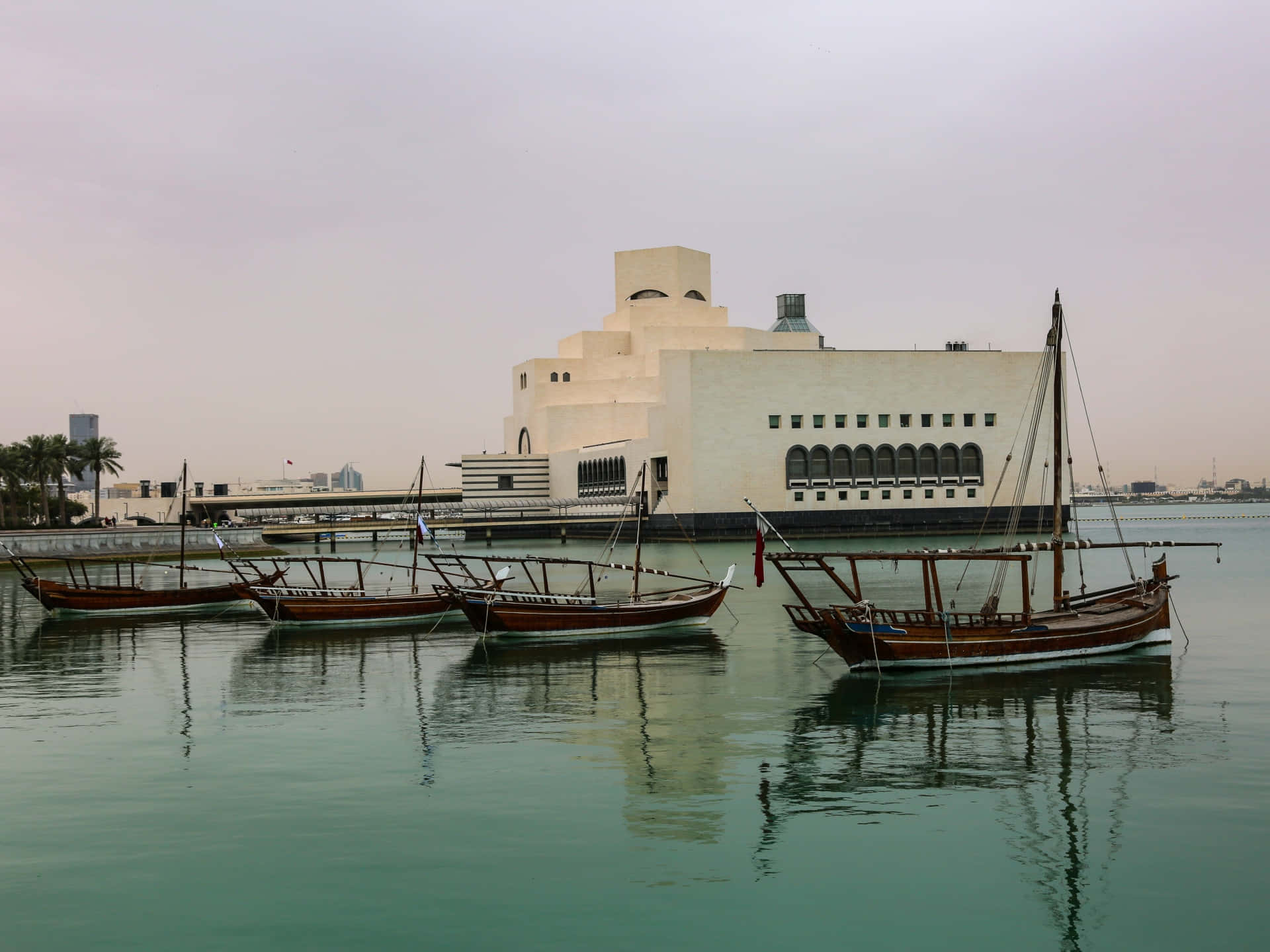 Majestic view of the Museum of Islamic Art with serene boats in the forefront, Doha, Qatar. Wallpaper